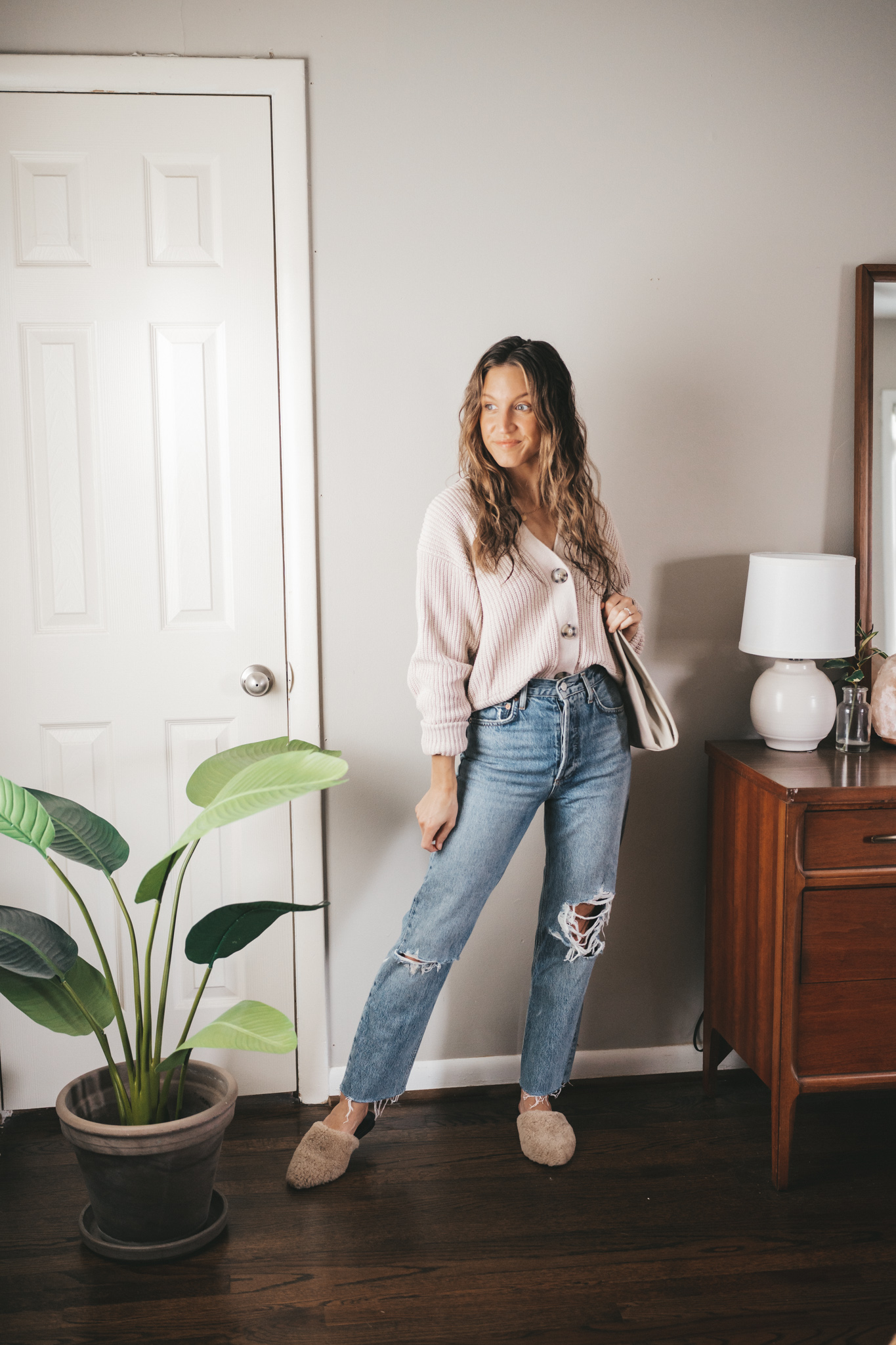 spring outfit with a taupe button front cardigan, distressed denim, and tan shearling mules
