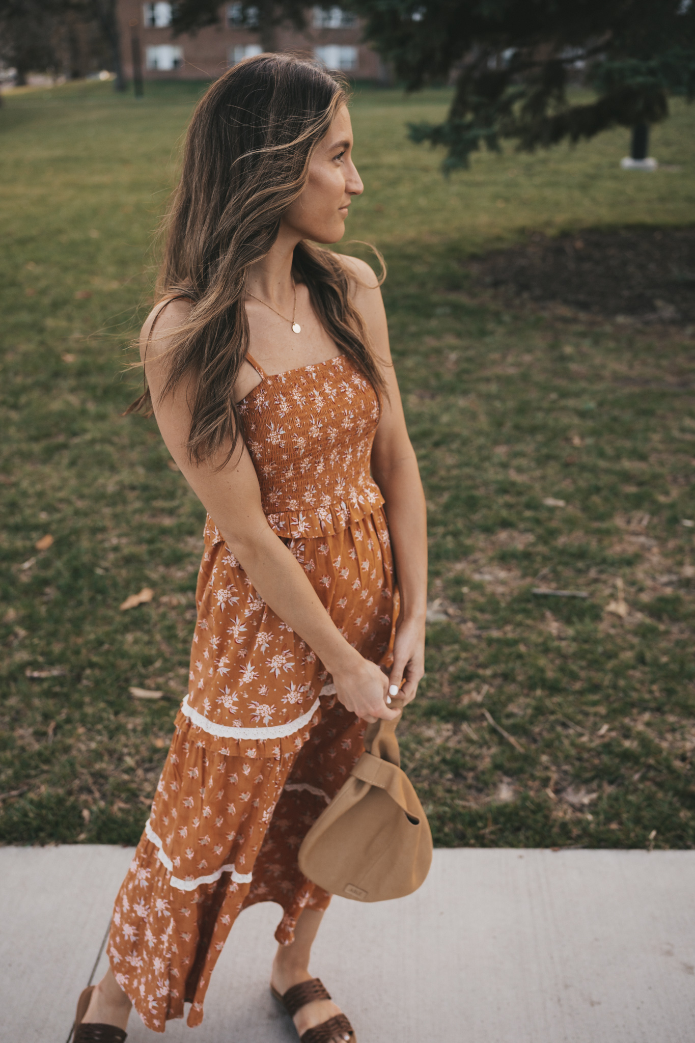 affordable spring dress or Easter dress; ashley wearing an orange floral patterned tiered midi dress standing on a sidewalk in a park