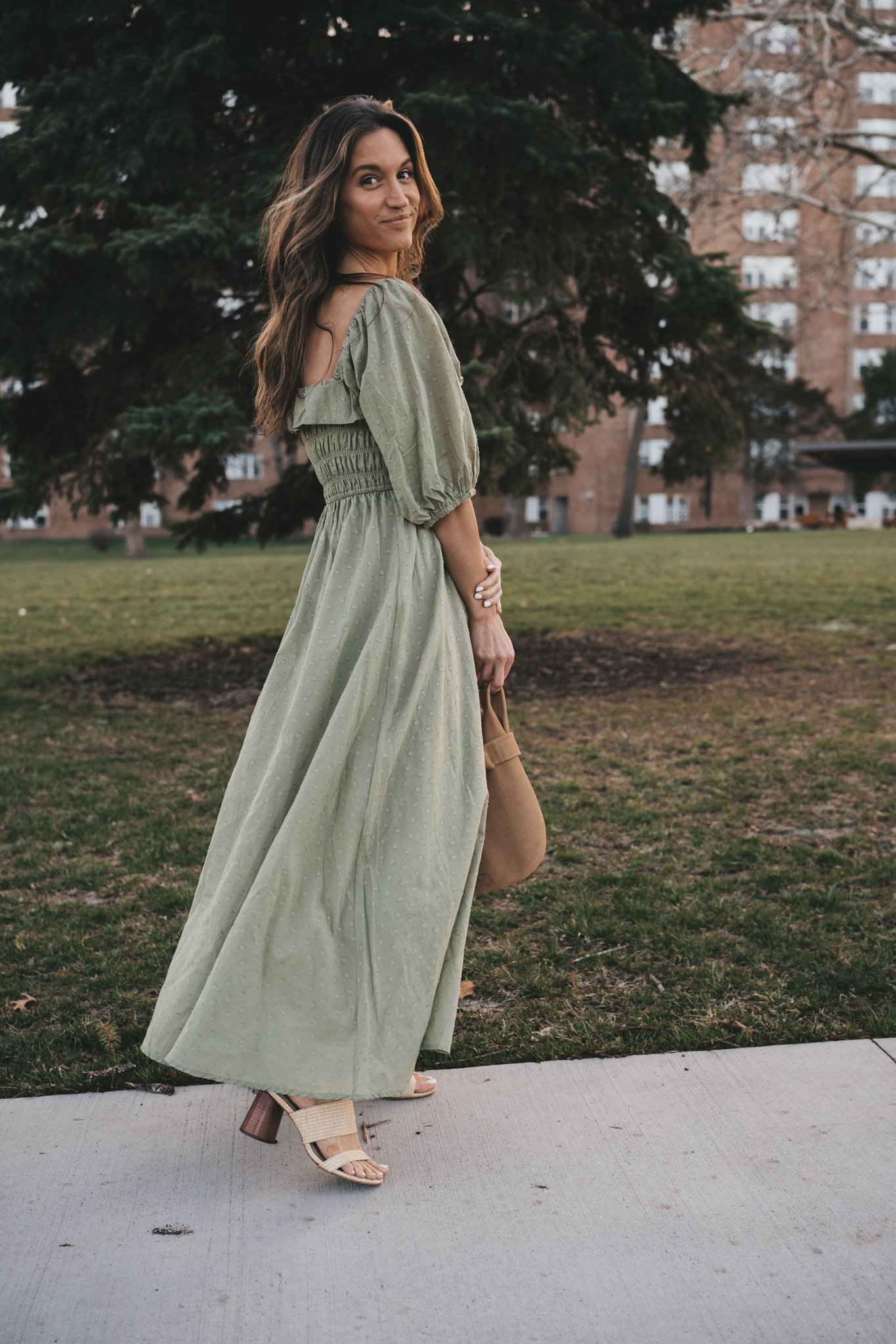 affordable spring dress or Easter dress; ashley wearing a sage green dress with puff sleeves with woven heeled sandals and a tan leather clutch