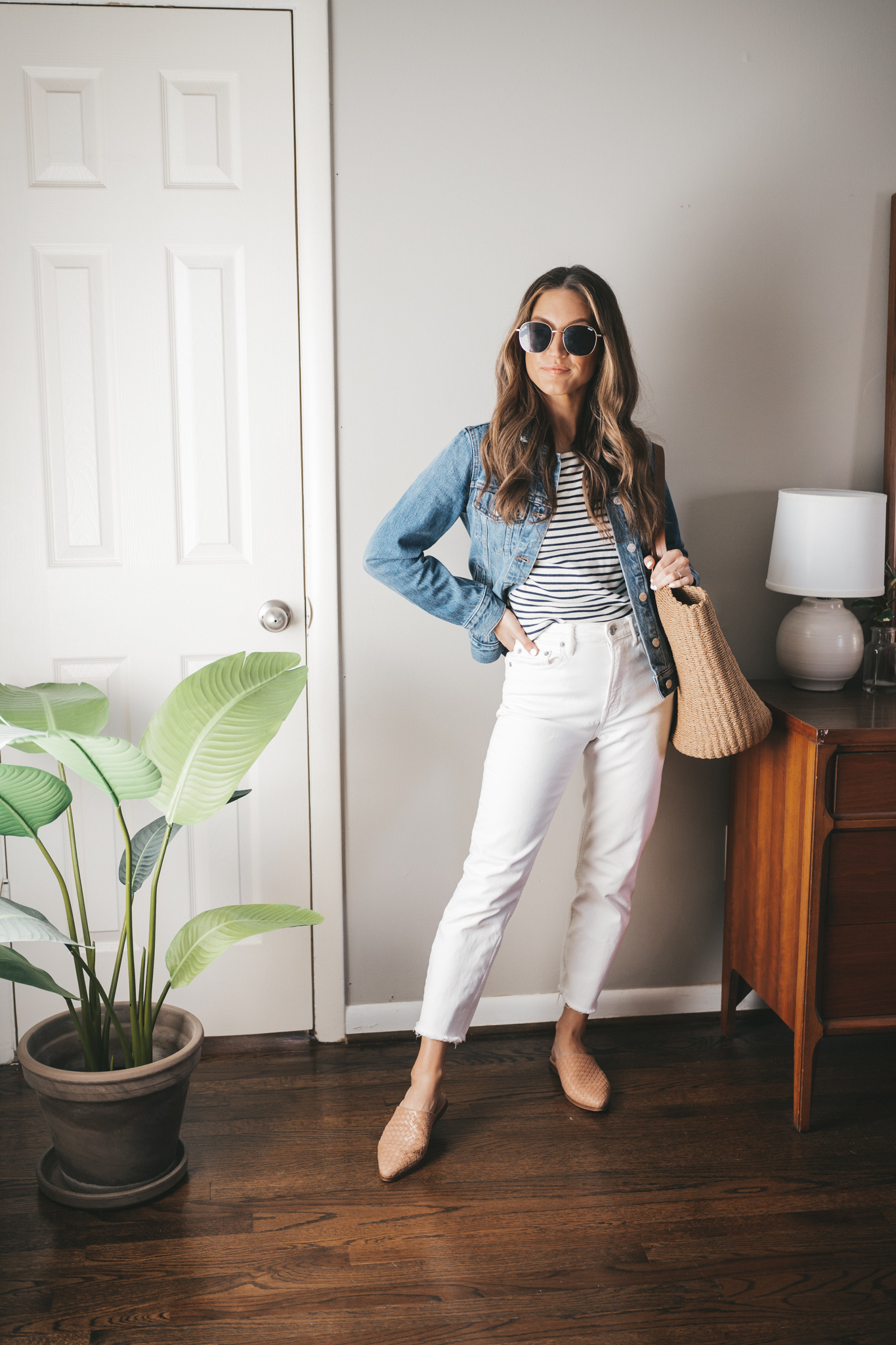spring outfit with a striped tee, denim jacket, white denim, woven mules and a straw tote bag