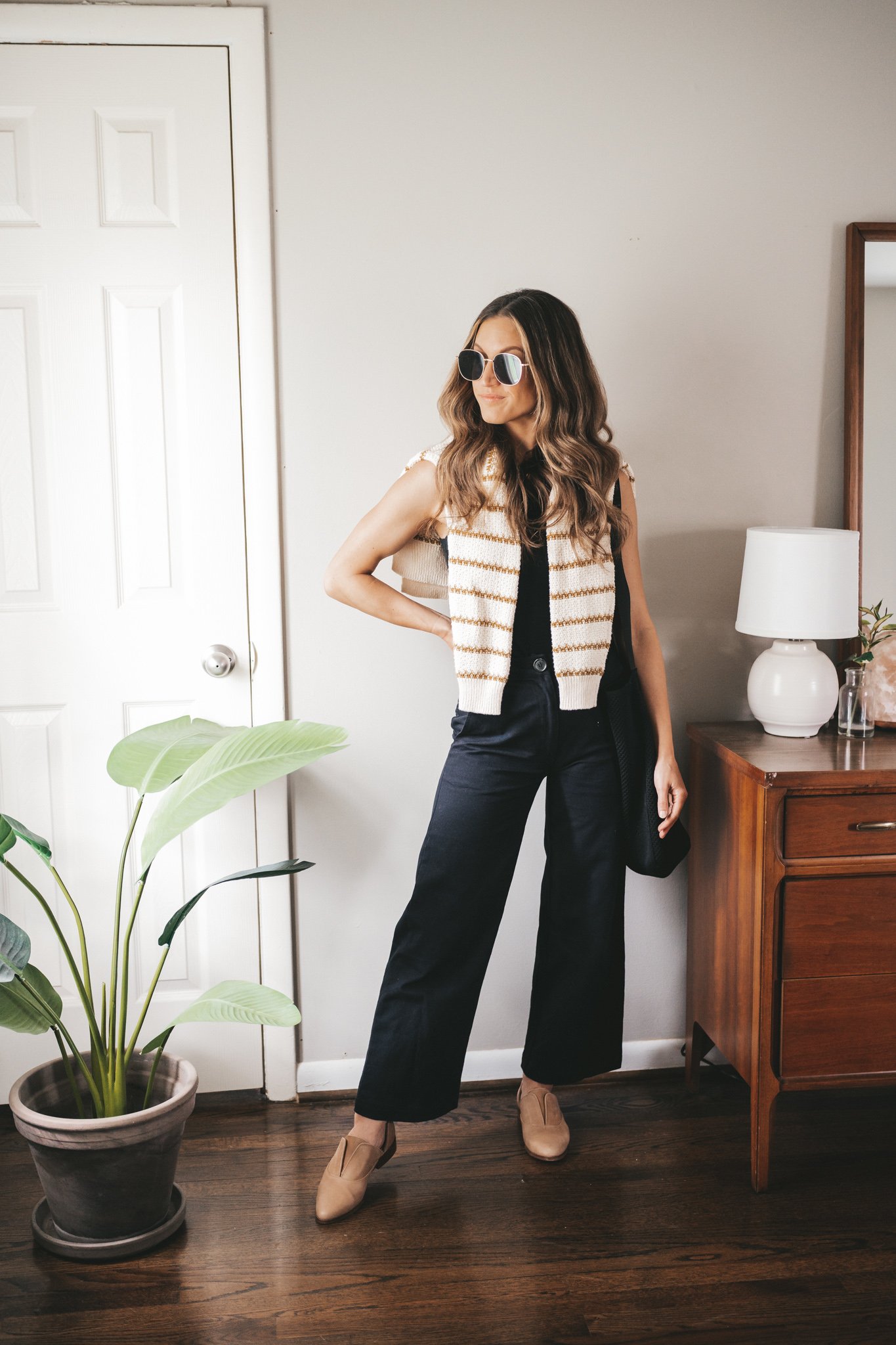 spring outfit with a black tank and a striped sweater worn over the shoulders, black wide leg cropped pants, and nude oxfords with gold framed sunglasses