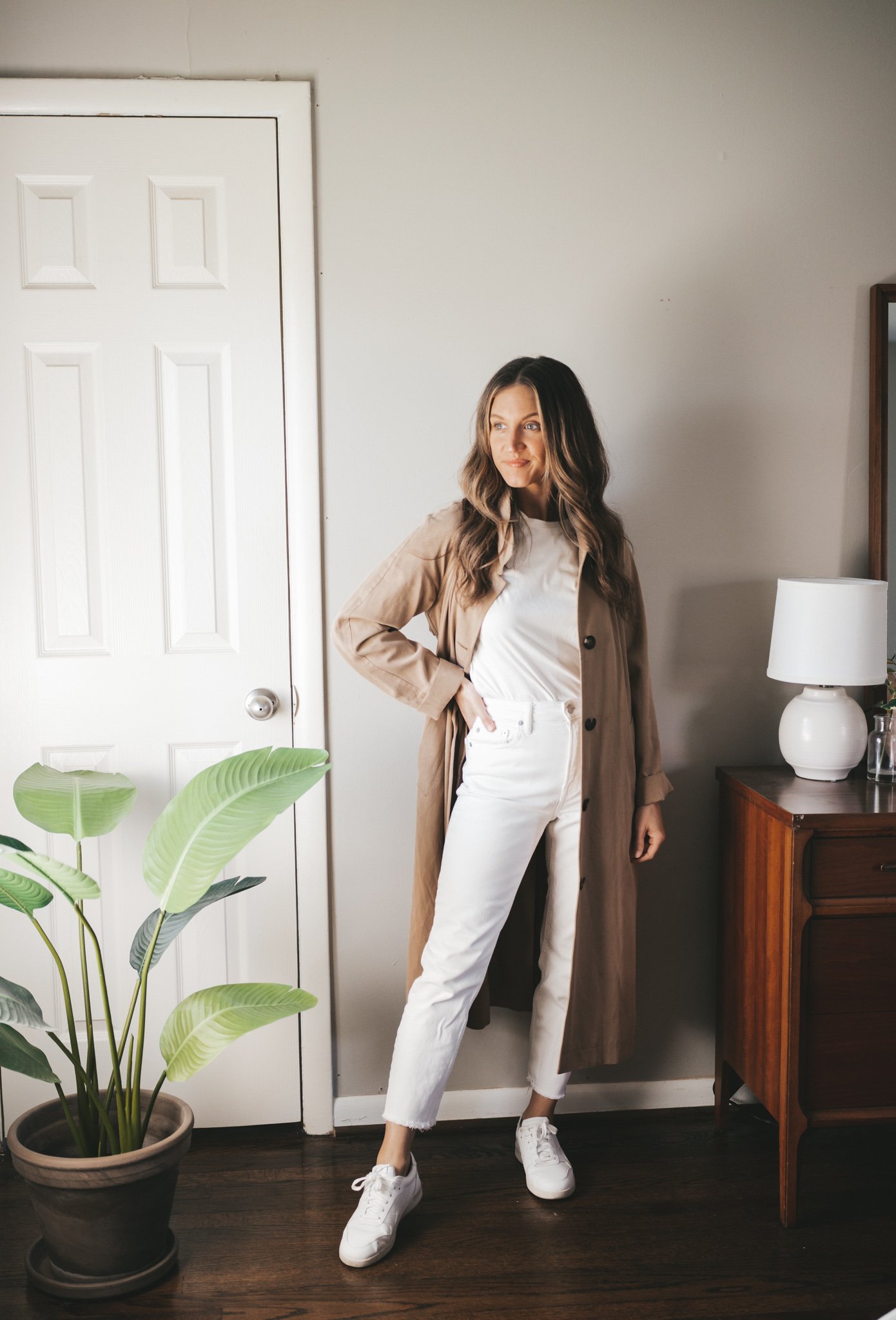 white denim outfit idea with a white tank, taupe trench coat, white denim, and white sneakers