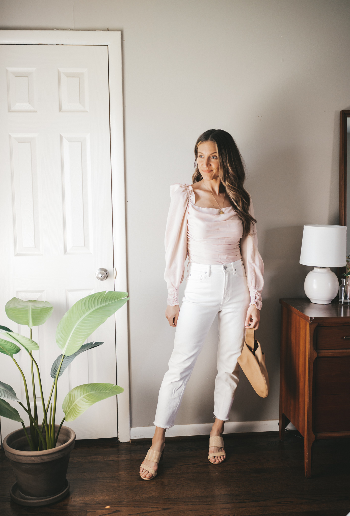white denim outfit idea with a blush puff sleeve top, white denim, heeled sandals and a clutch bag