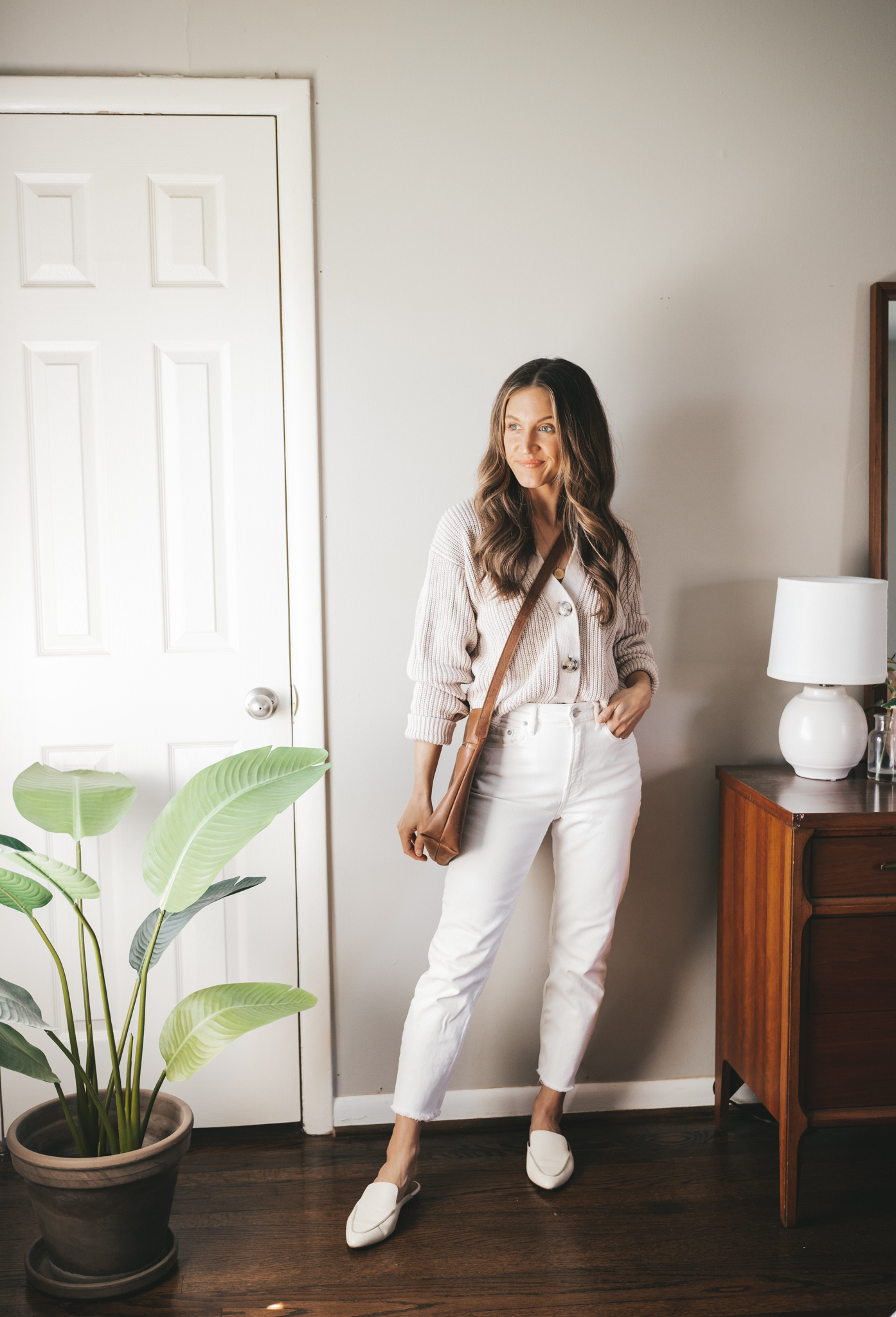 white denim outfit idea with a taupe button front cardigan, white denim, white mules and a brown crossbody bag