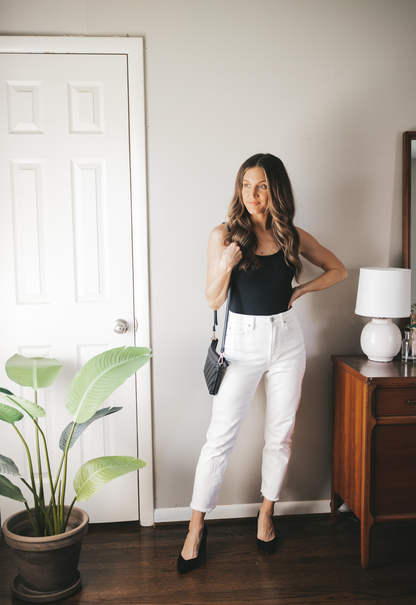 white denim outfit idea with a black bodysuit, white denim, black pumps, and a black quilted bag