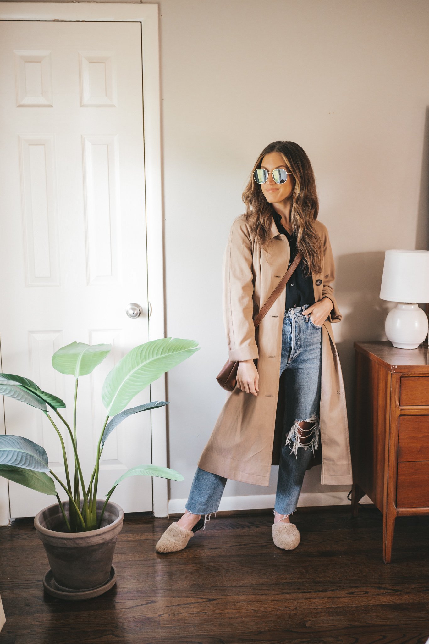 outfit for spring with a black button down, trench coat, distressed denim, and shearling mules