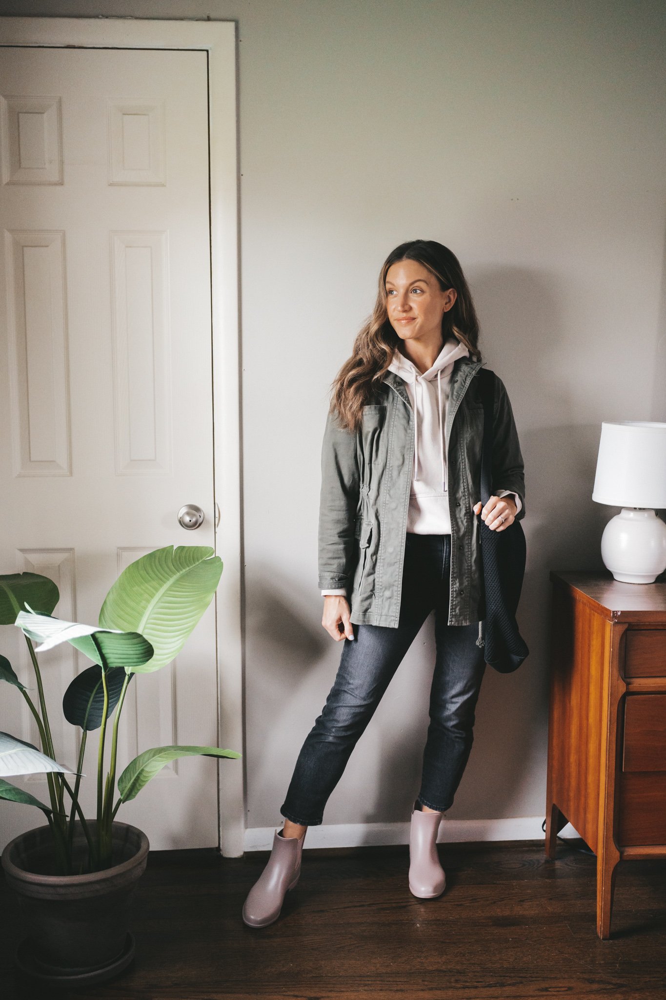 outfit for spring with a taupe hoodie, green utility jacket, washed black denim, and taupe rainboots