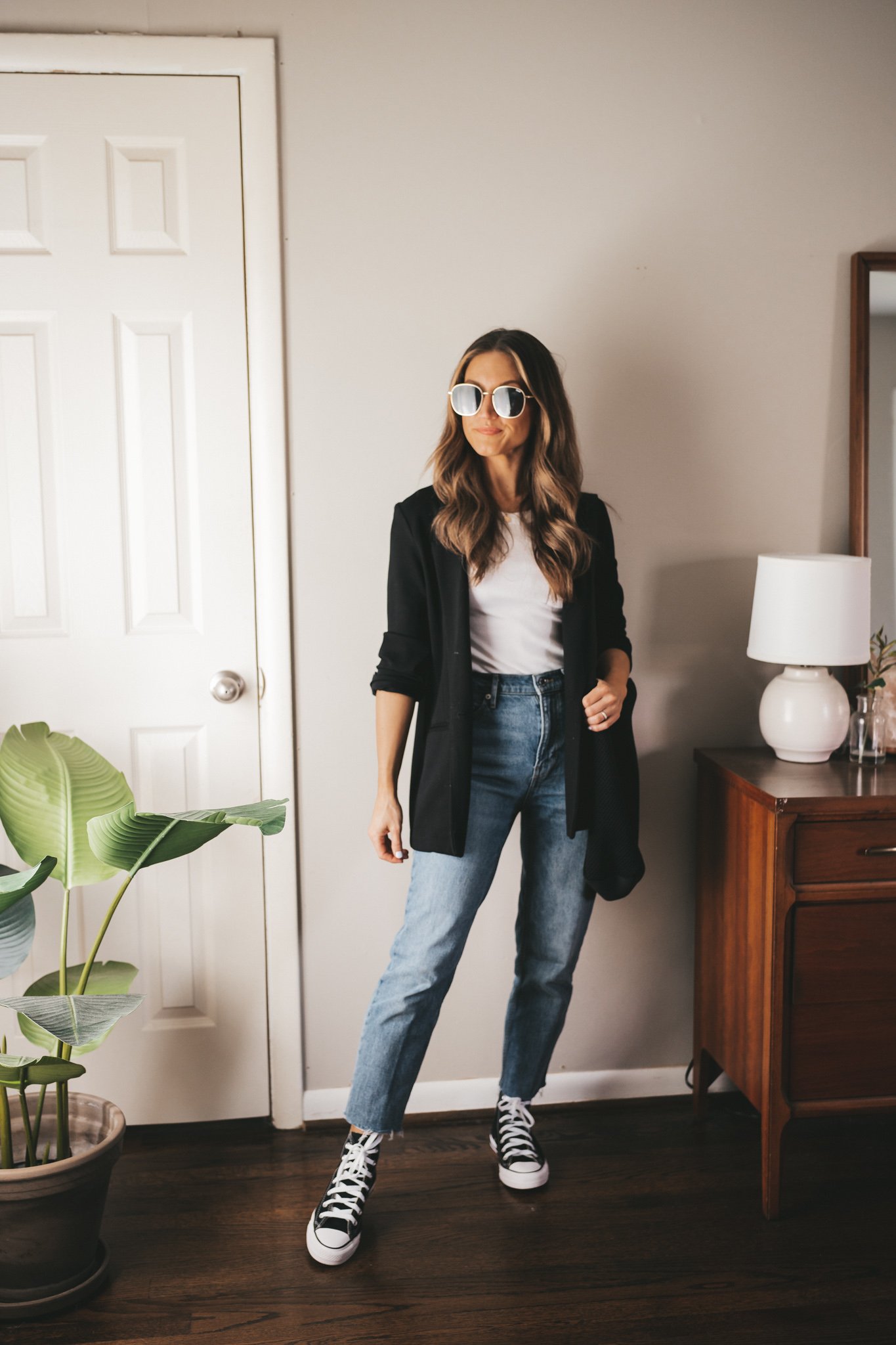 ashley wearing a white tank, black blazer, mid-wash denim, and black high top converse
