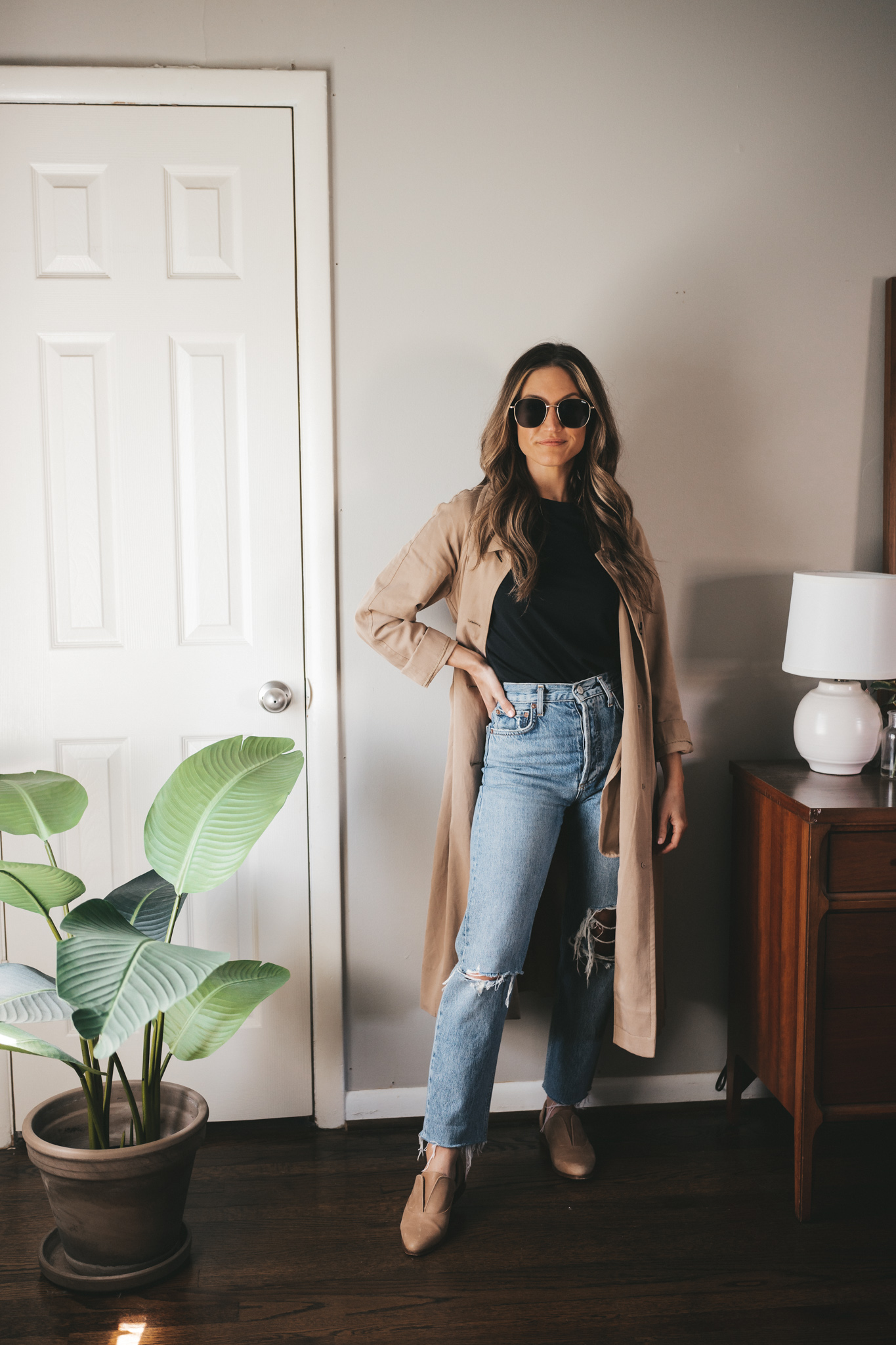 ashley wearing a black tee, tan trench coat, distressed denim, and tan oxfords
