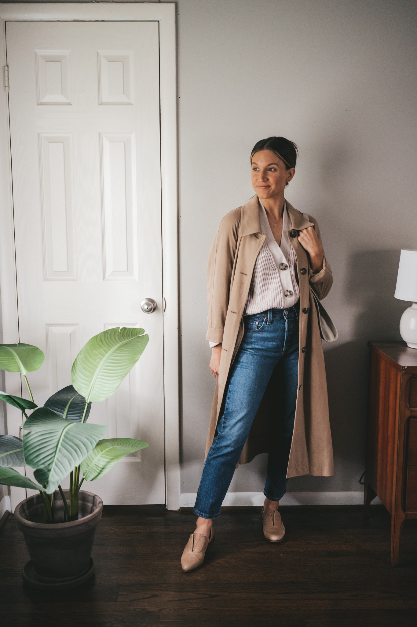 ashley wearing a button front cropped taupe cardigan under a tan trench coat with dark wash denim, and nude oxfords