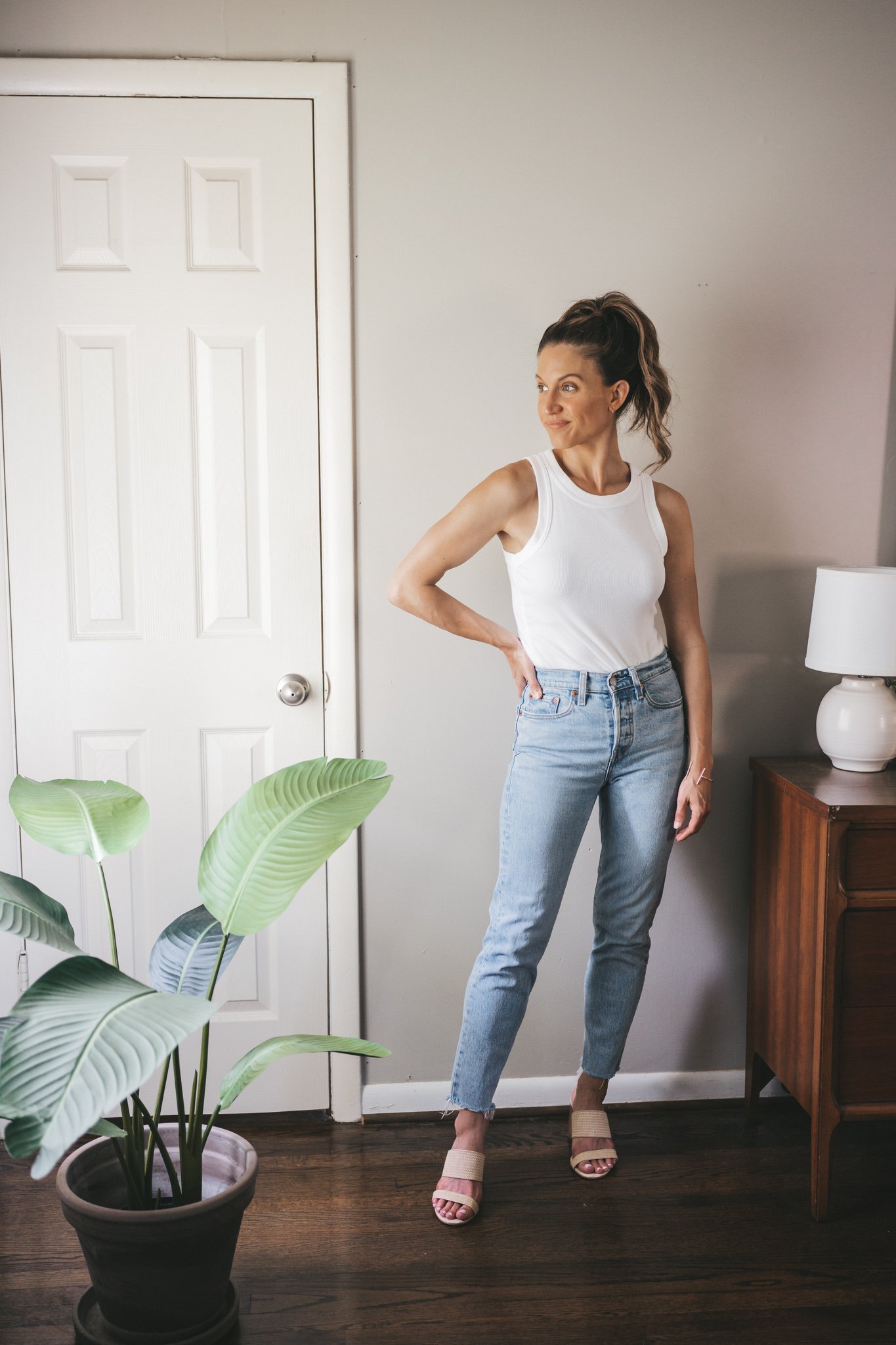 ashley wearing a white tank, straight denim, and woven heeled sandals