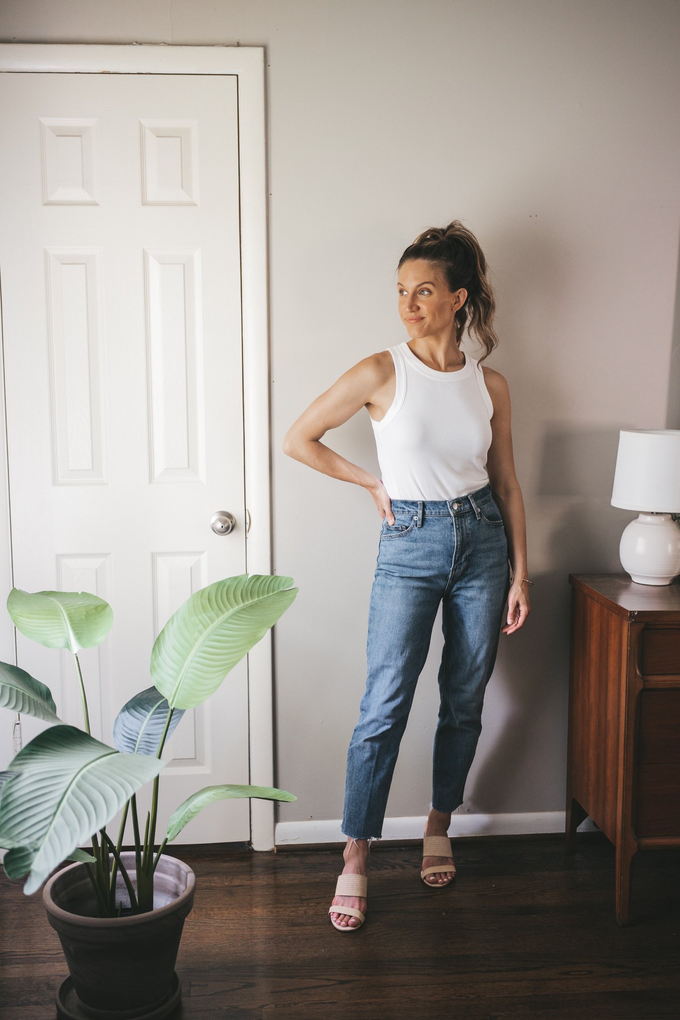ashley wearing a white tank, straight denim, and woven heeled sandals