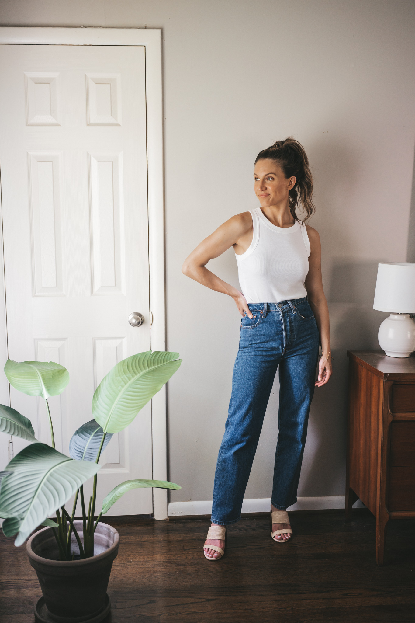 ashley wearing a white tank, straight denim, and woven heeled sandals
