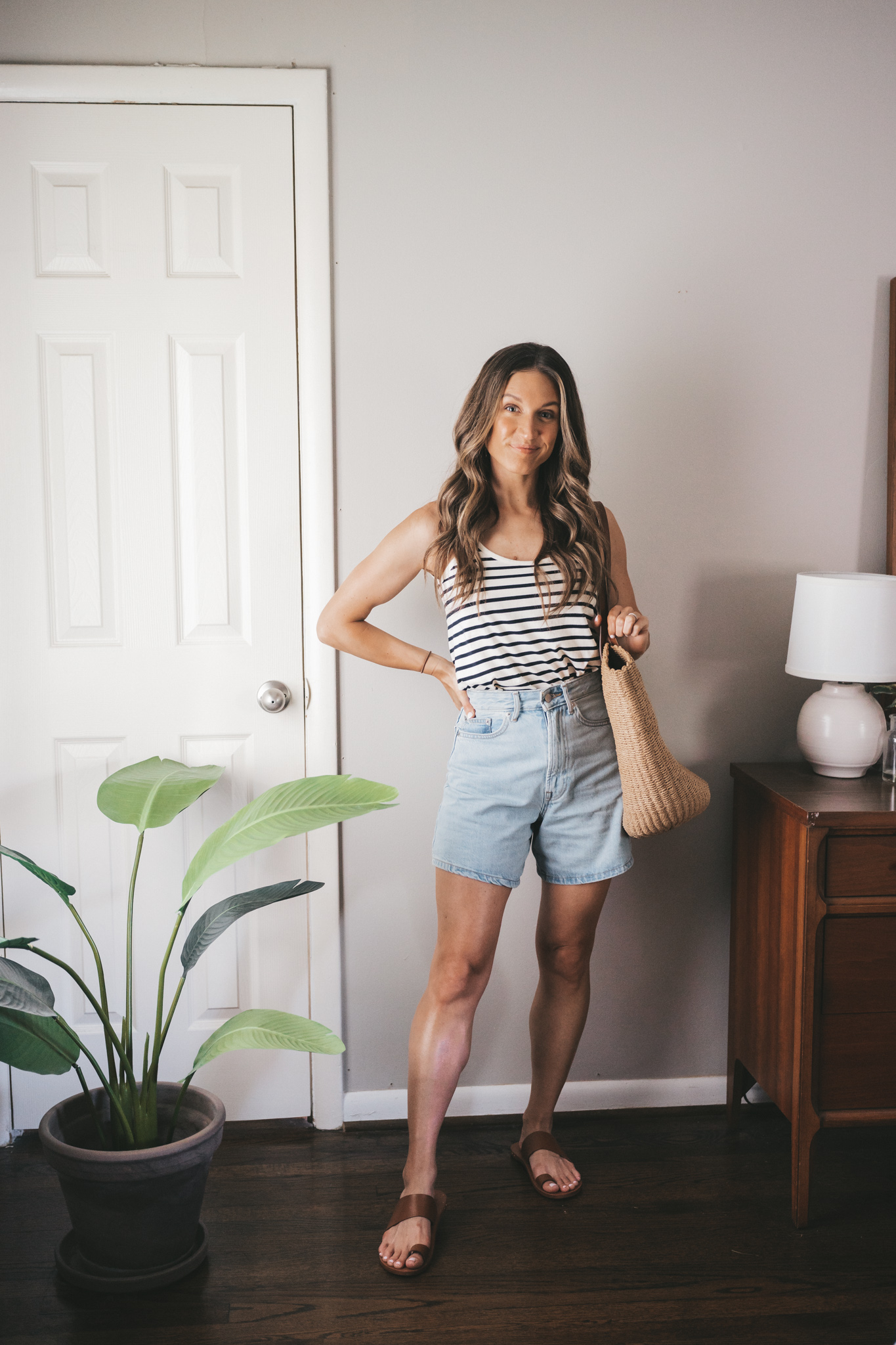 ashley wearing a white and navy striped tank, light wash denim shorts, and brown leather sandals