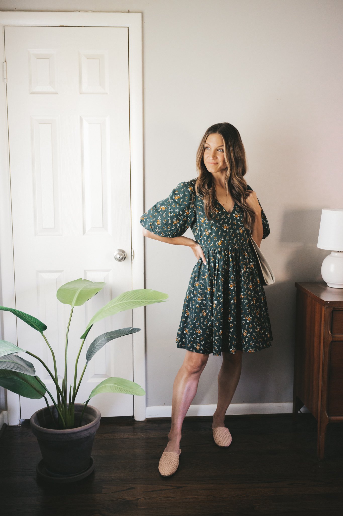 ashley wearing a green floral mini dress with puff sleeves and woven mules