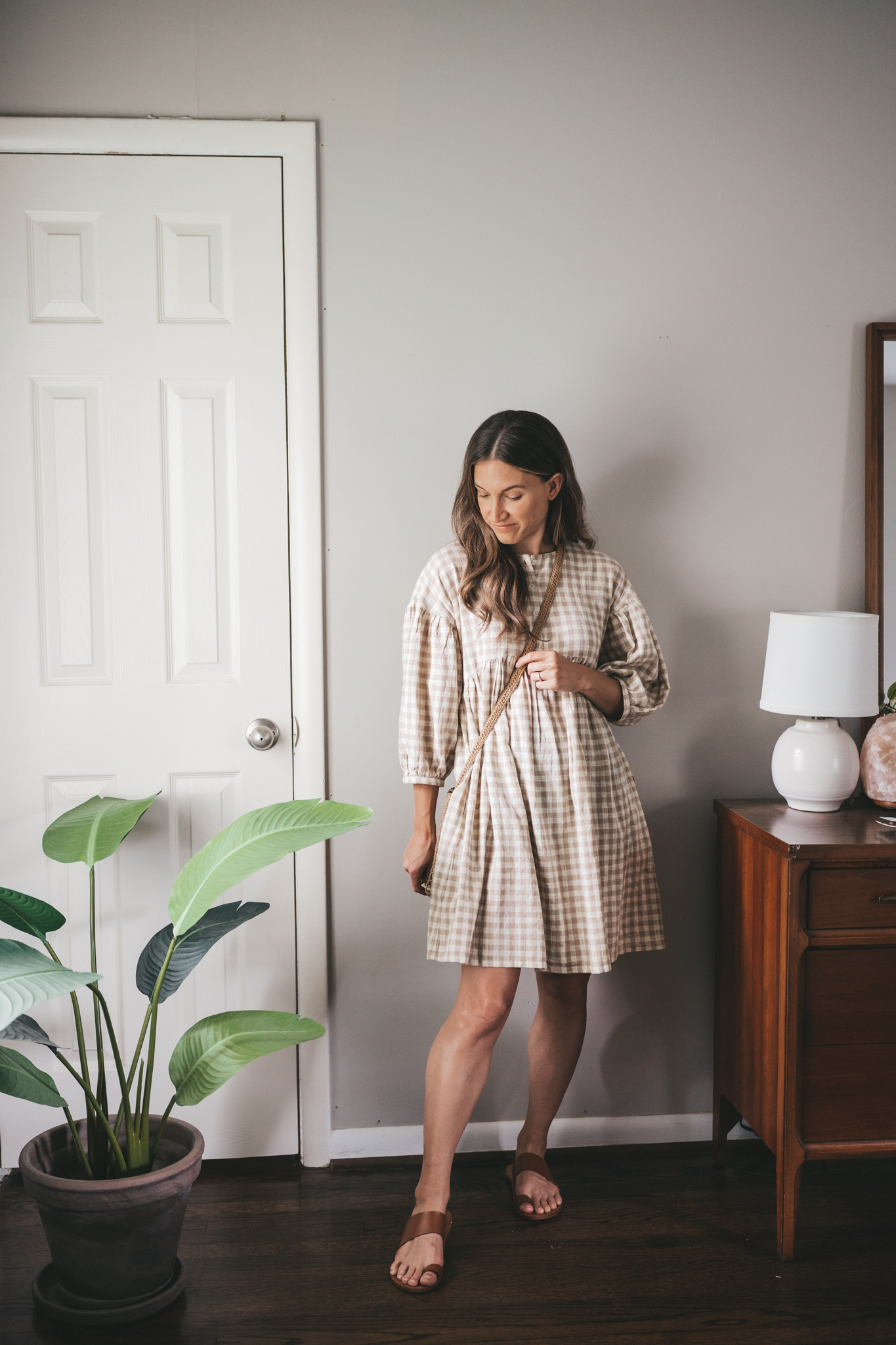 daily look with a white and tan gingham swing dress, brown leather sandals, and a straw crossbody bag