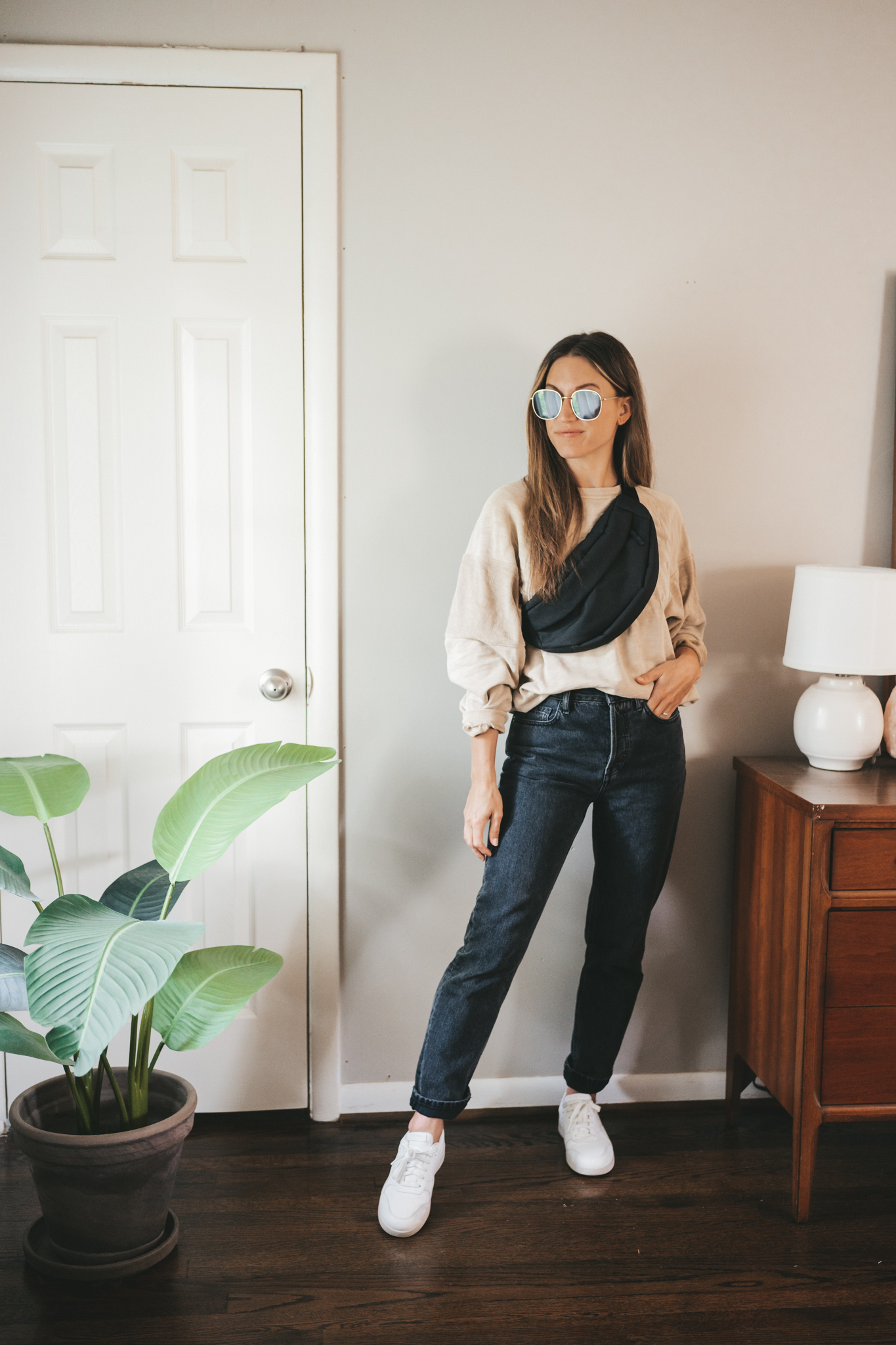 daily look with a tan oversized sweatshirt, black denim, white sneakers, and a black belt bag