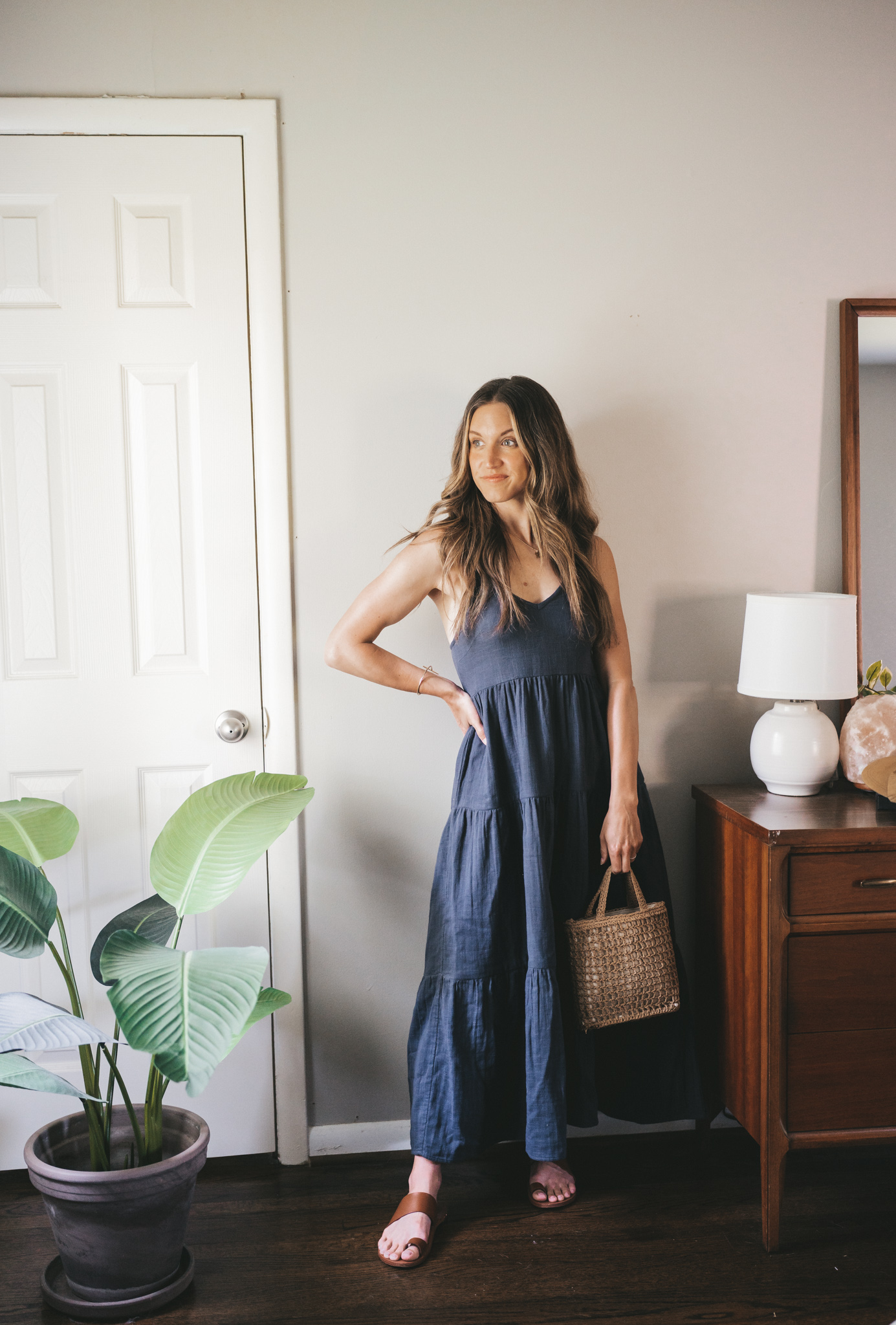 daily look with a washed black tiered maxi dress, brown leather sandals, and a straw bag