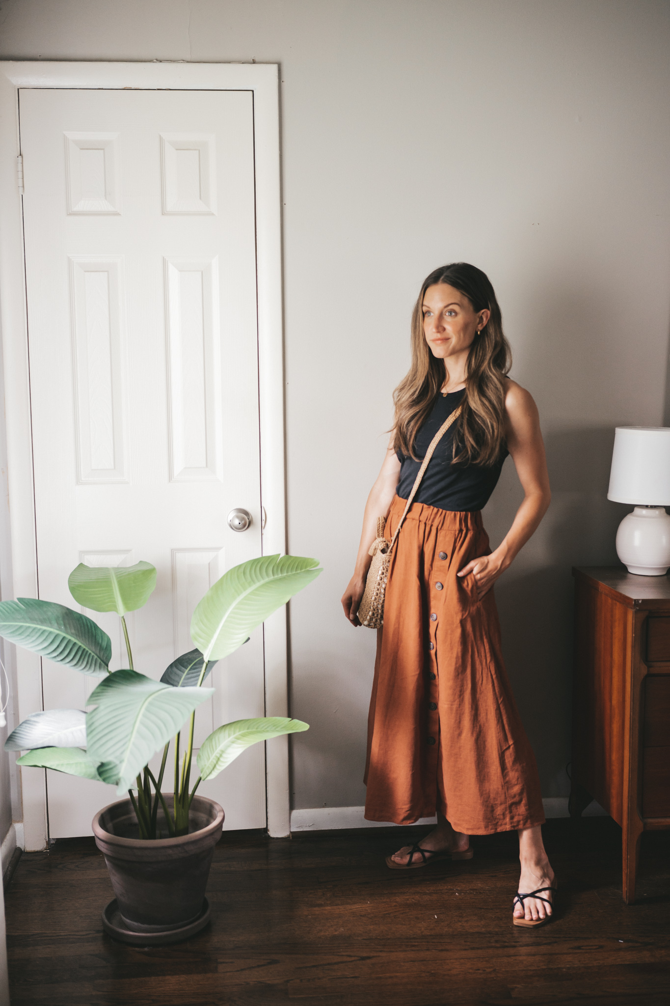 daily look with a black tank, rust colored button front midi dress, black strappy sandals, and a straw crossbody bag
