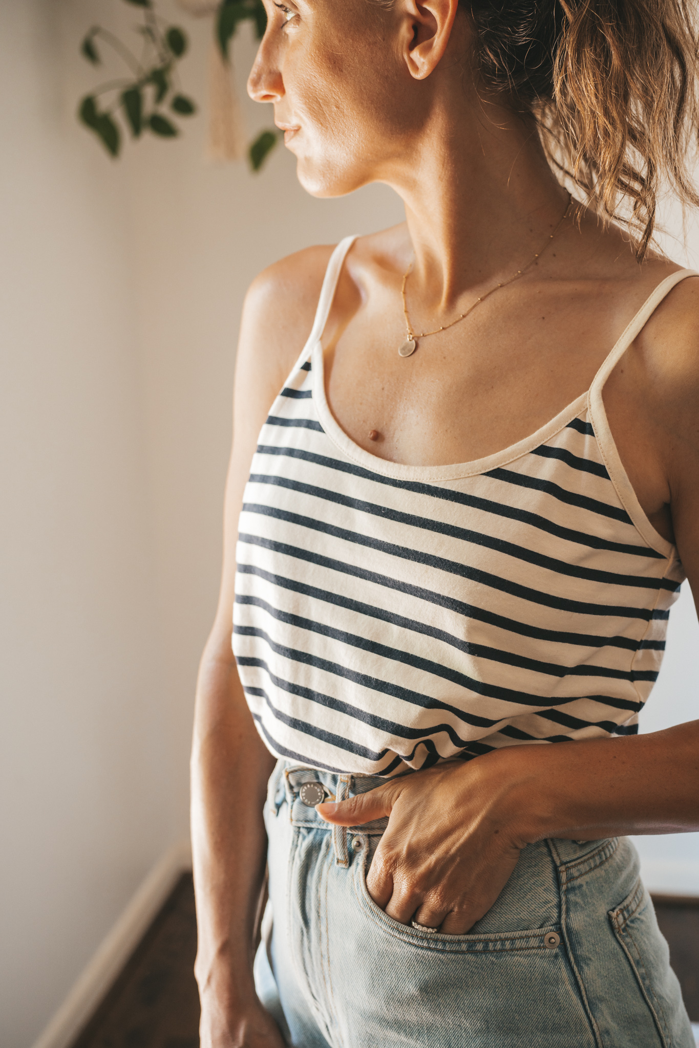 ashley wearing a striped tank, light wash denim shorts, white sandals, and a woven tote bag