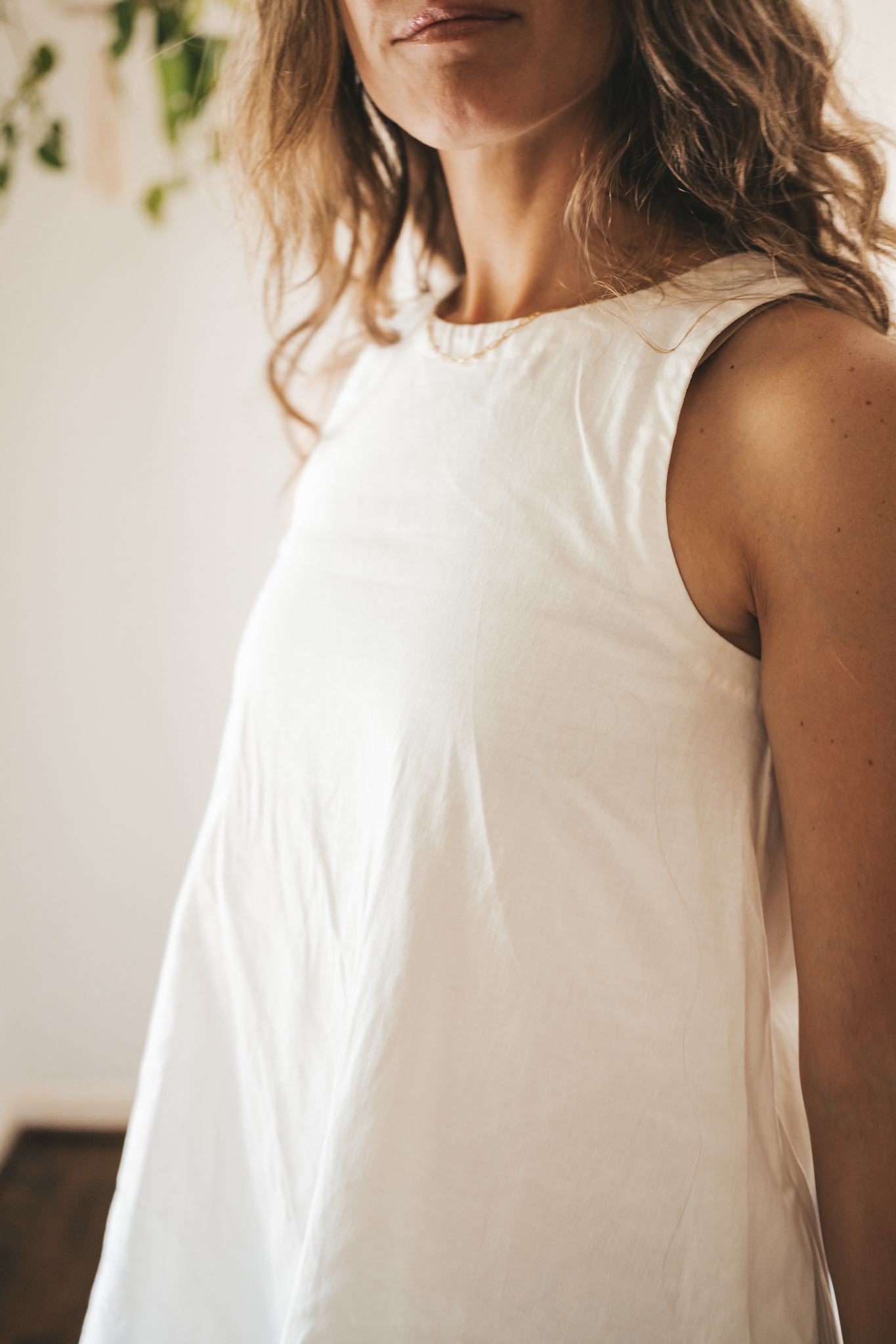 ashley wearing a white linen shift dress, nude sandals, and a woven bag