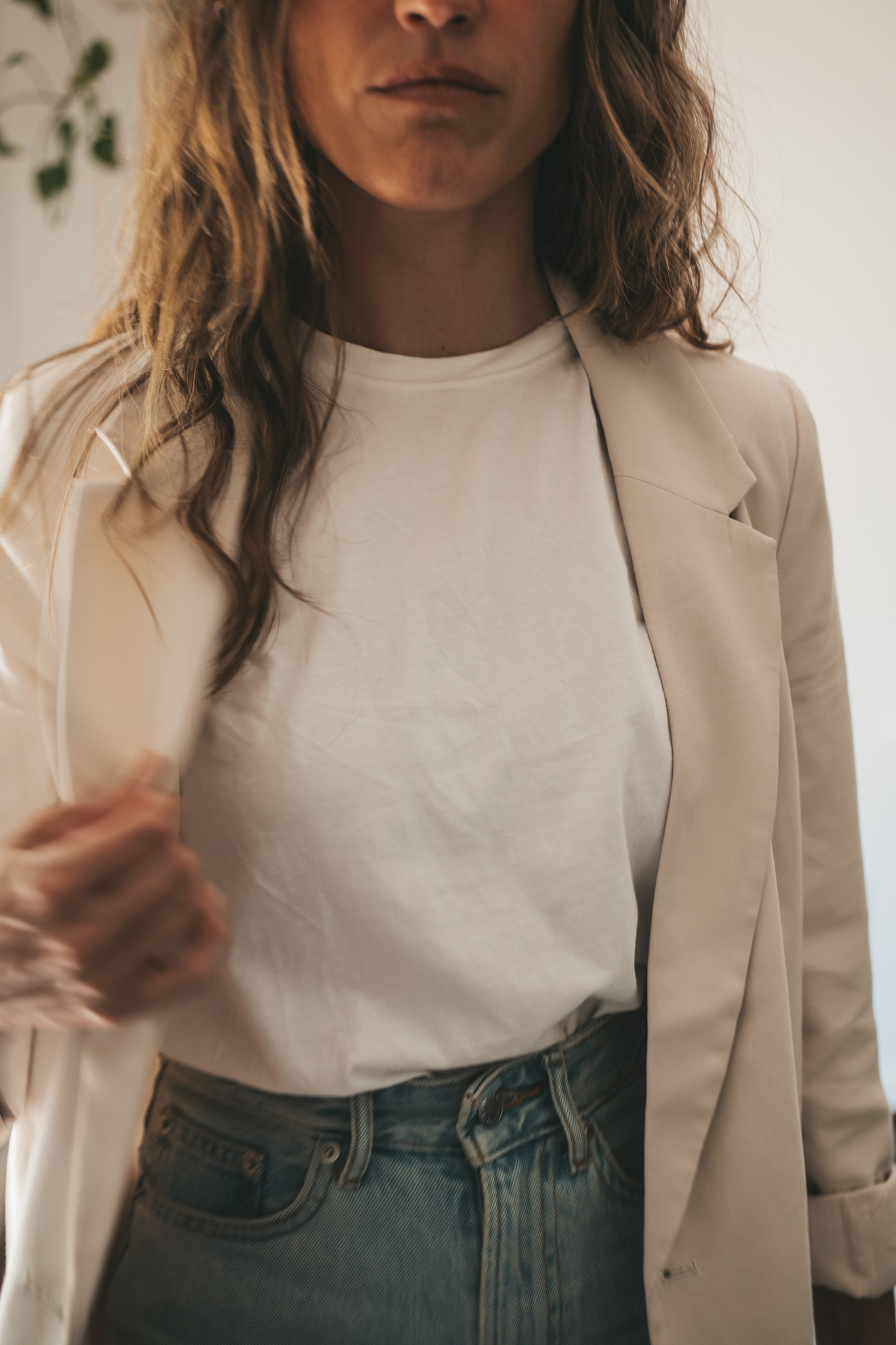 ashley wearing a white tee, beige oversized blazer, light wash long length denim shorts, white sneakers and a beige baseball cap with a gray shoulder bag