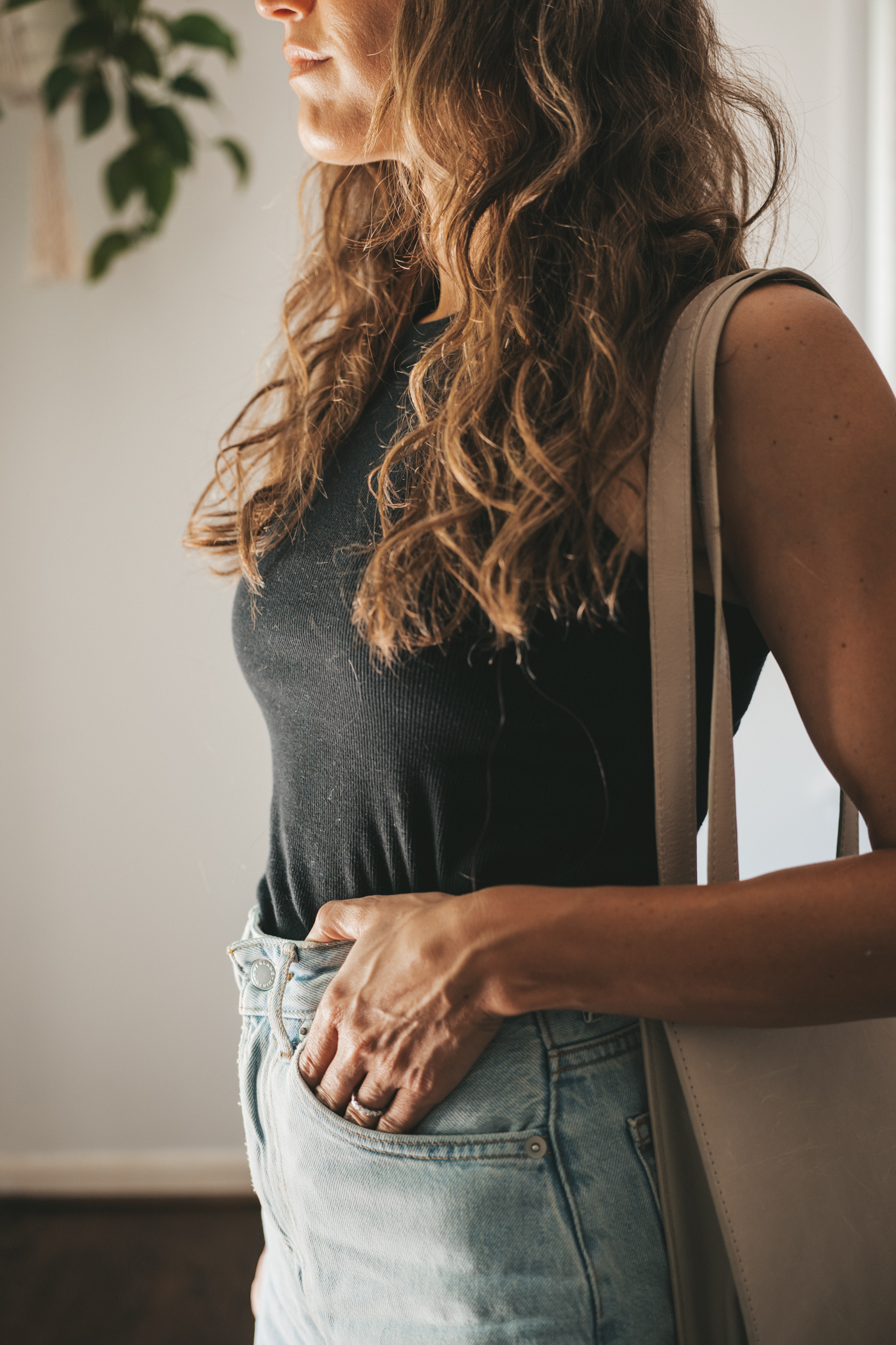 ashley wearing a black ribbed tank, light wash denim shorts, white sneakers, a beige baseball cap, and a gray leather shoulder bag