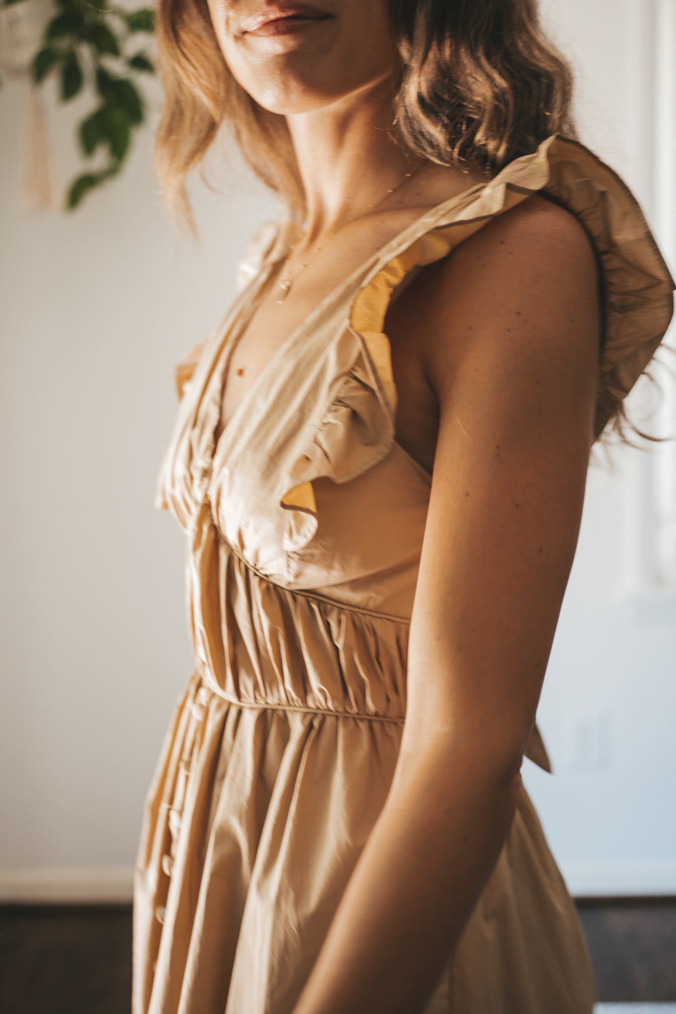 ashley wearing a tan midi dress with fabric buttons, nude sandals, and a woven bag