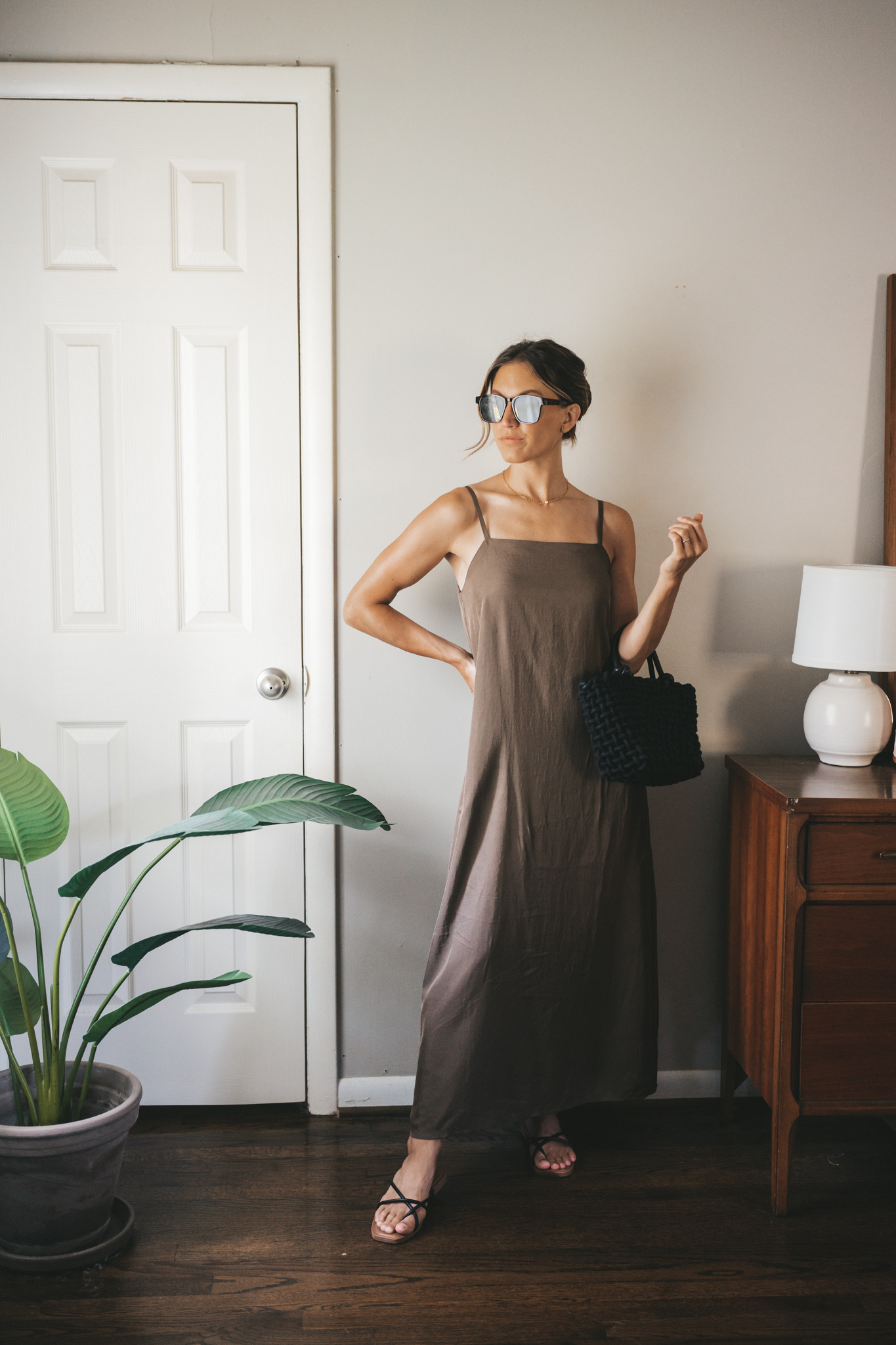 ashley wearing a green slip dress, black woven bag, black strappy sandals, and tortoise shell sunglasses