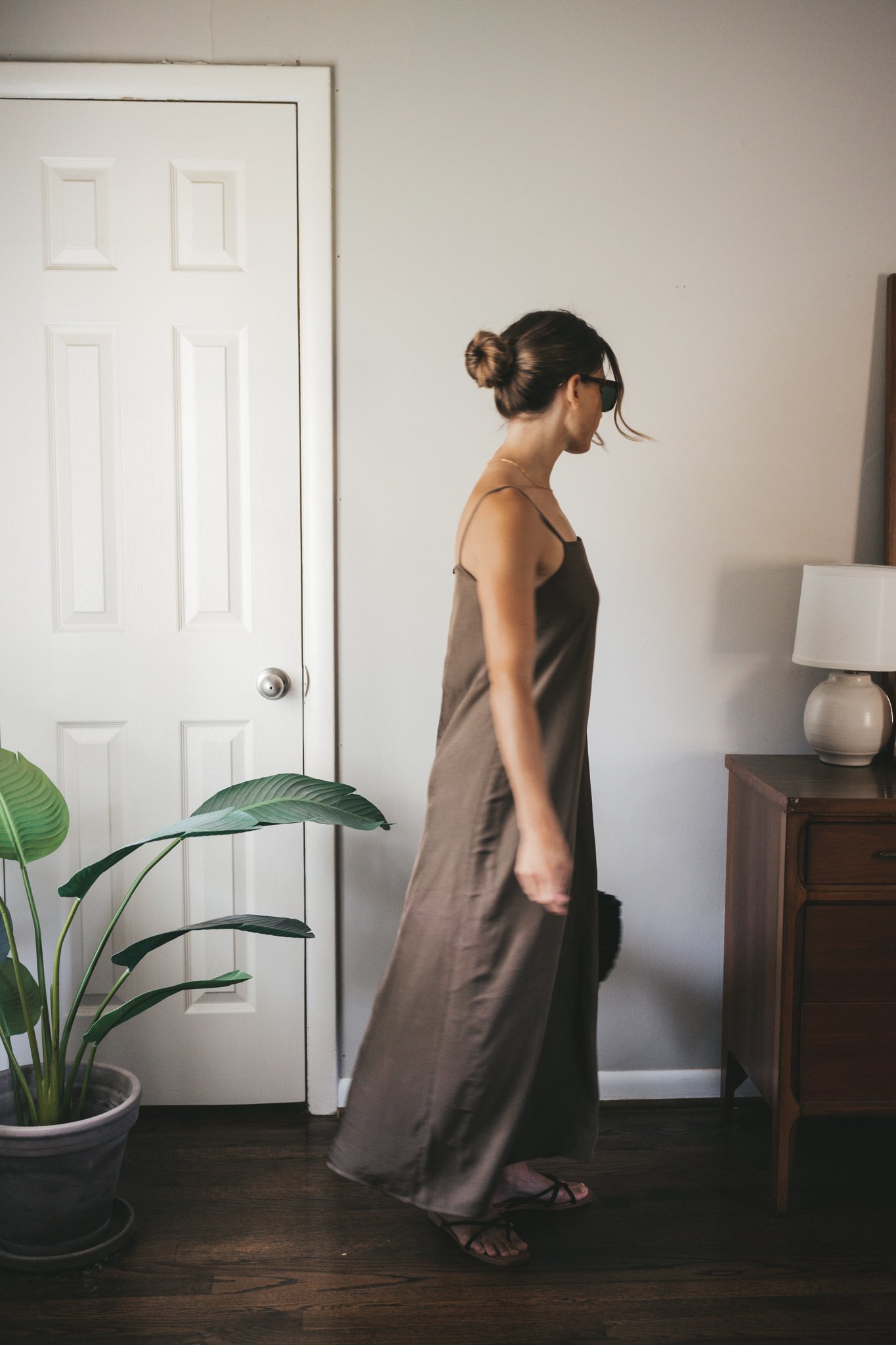 ashley wearing a green slip dress, black woven bag, black strappy sandals, and tortoise shell sunglasses
