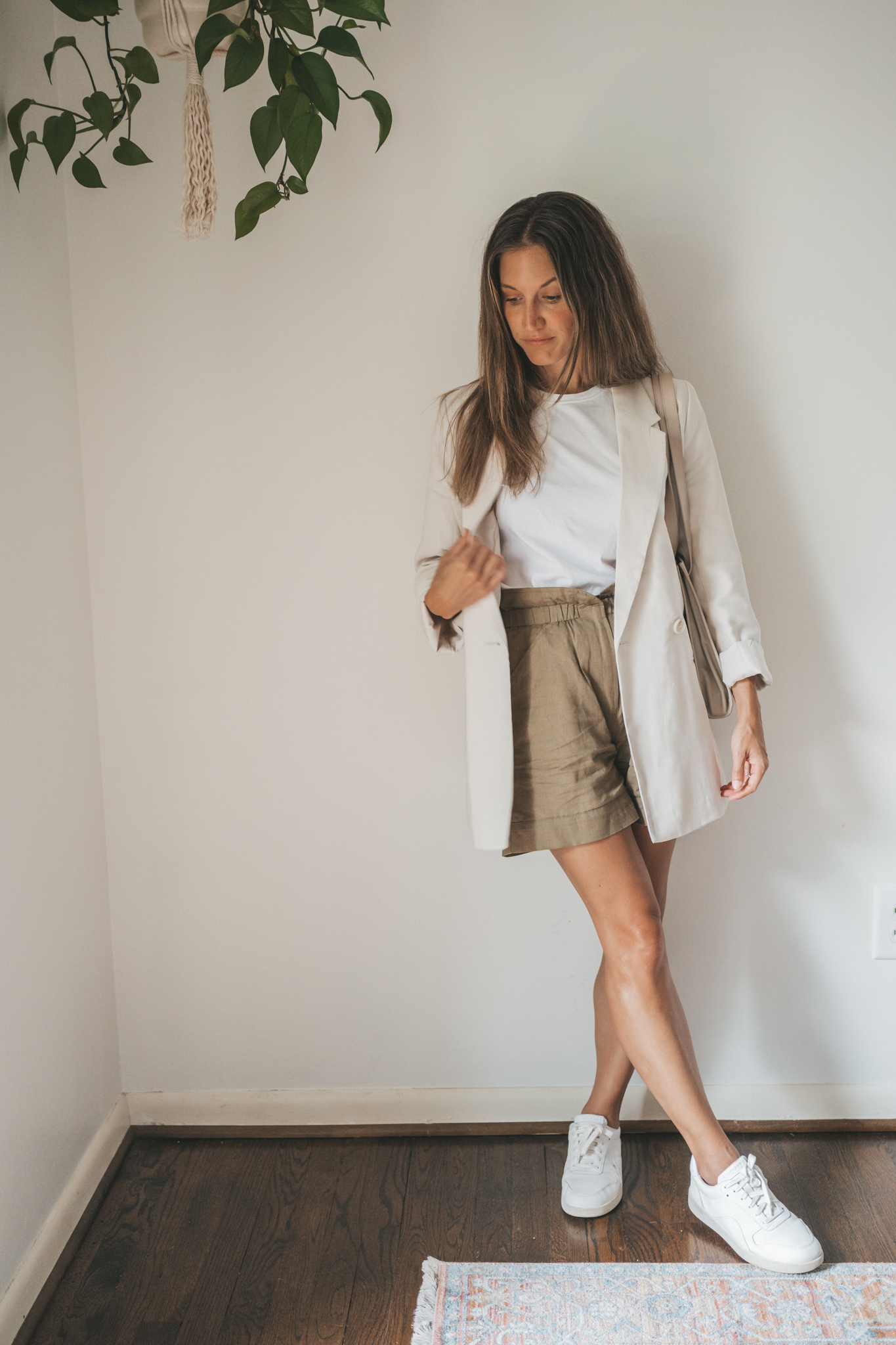 ashley wearing a white tee, beige oversized blazer, olive green paperbag shorts, white sneakers, and a gray shoulder bag