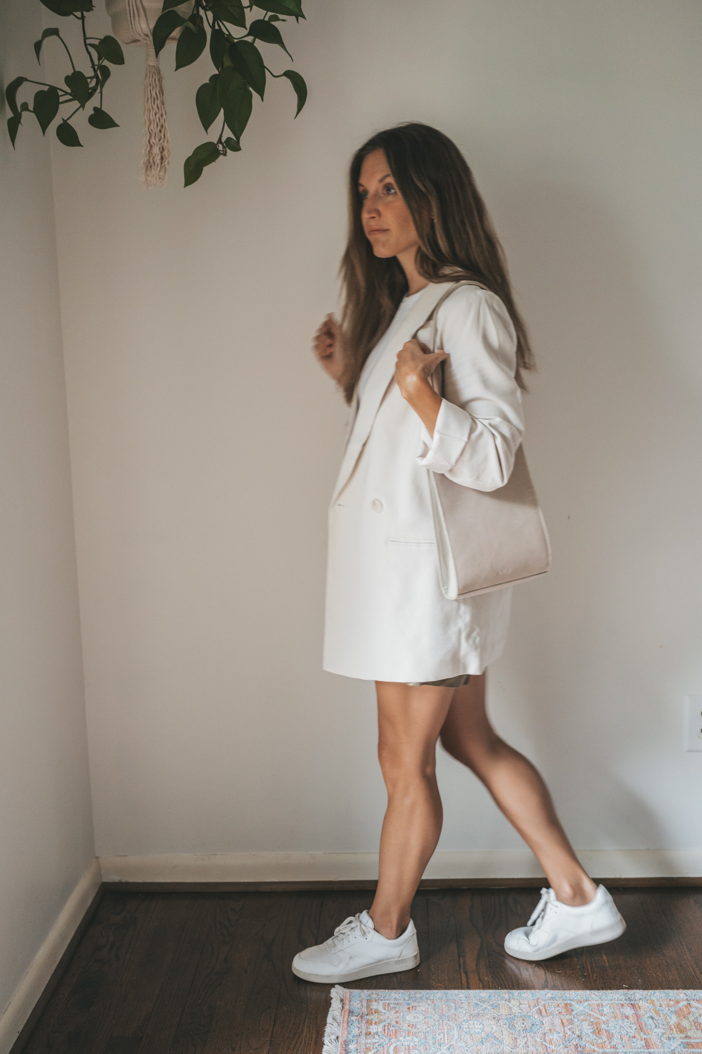 ashley wearing a white tee, beige oversized blazer, olive green paperbag shorts, white sneakers, and a gray shoulder bag