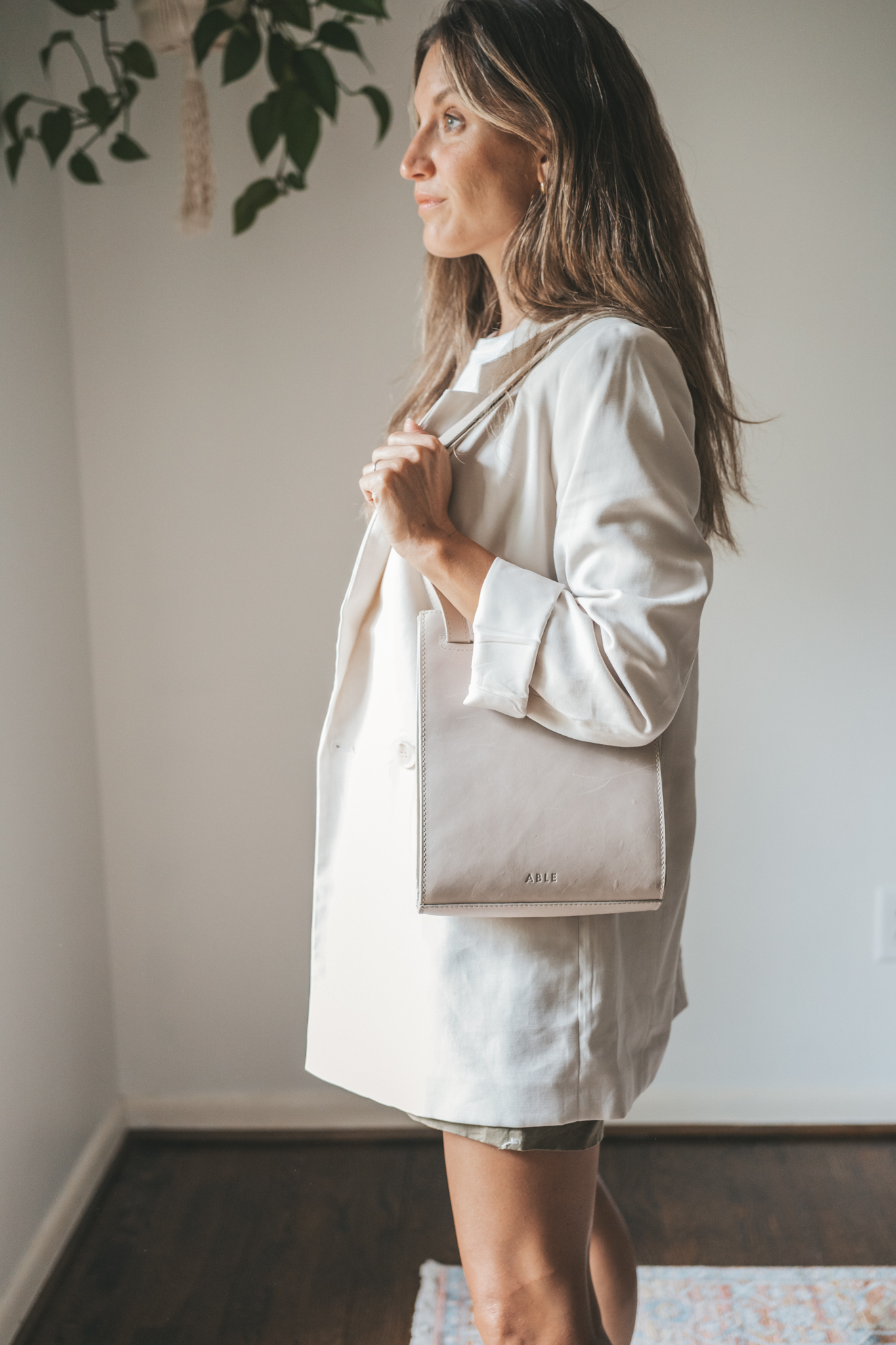 ashley wearing a white tee, beige oversized blazer, olive green paperbag shorts, white sneakers, and a gray shoulder bag