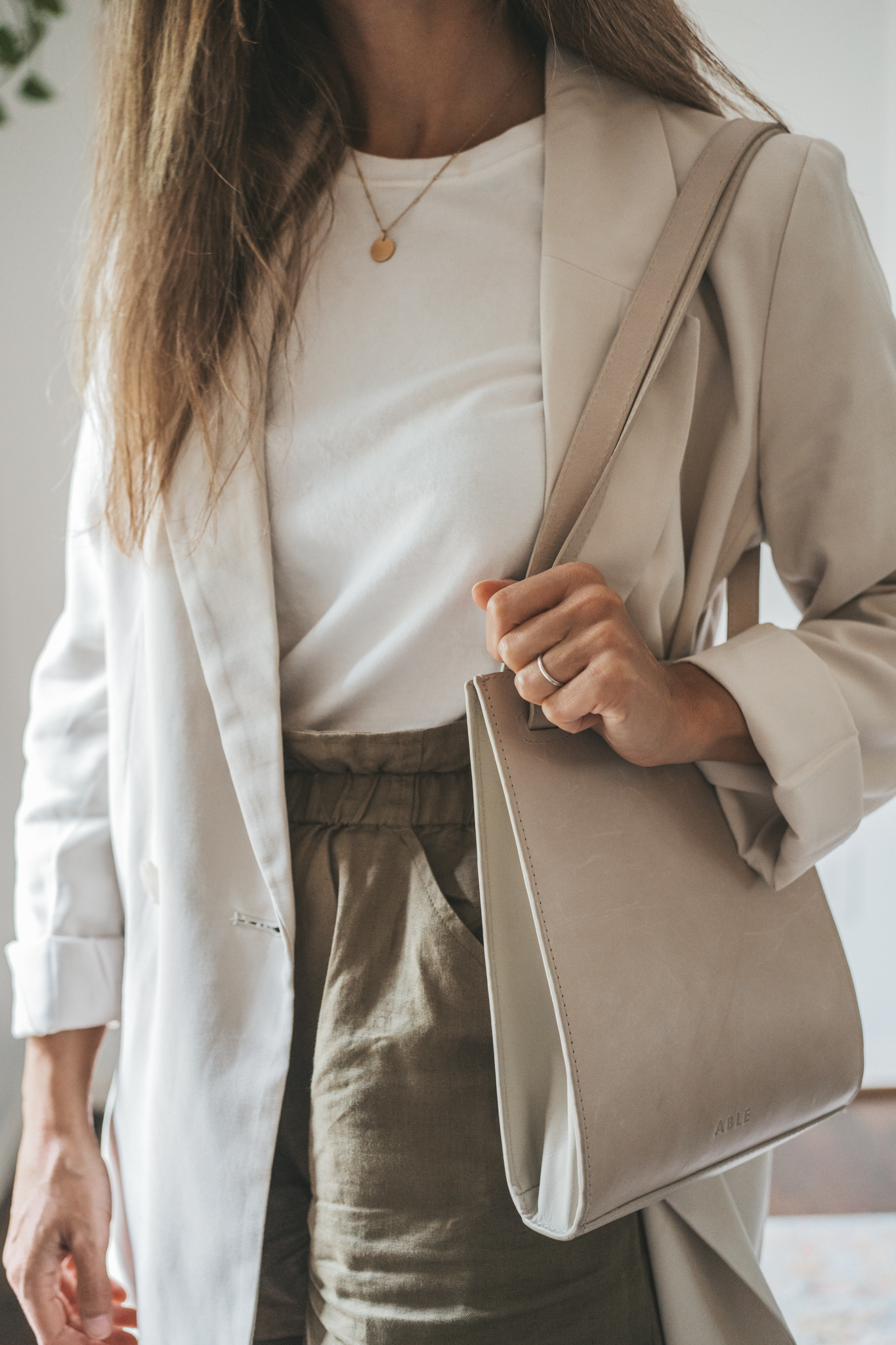ashley wearing a white tee, beige oversized blazer, olive green paperbag shorts, white sneakers, and a gray shoulder bag