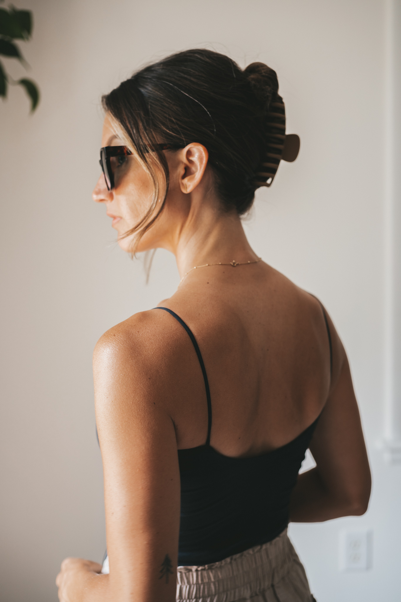 ashley wearing a black cropped tank, tan linen shorts, black strappy sandals, tortoise shell sunglasses and a black woven bag