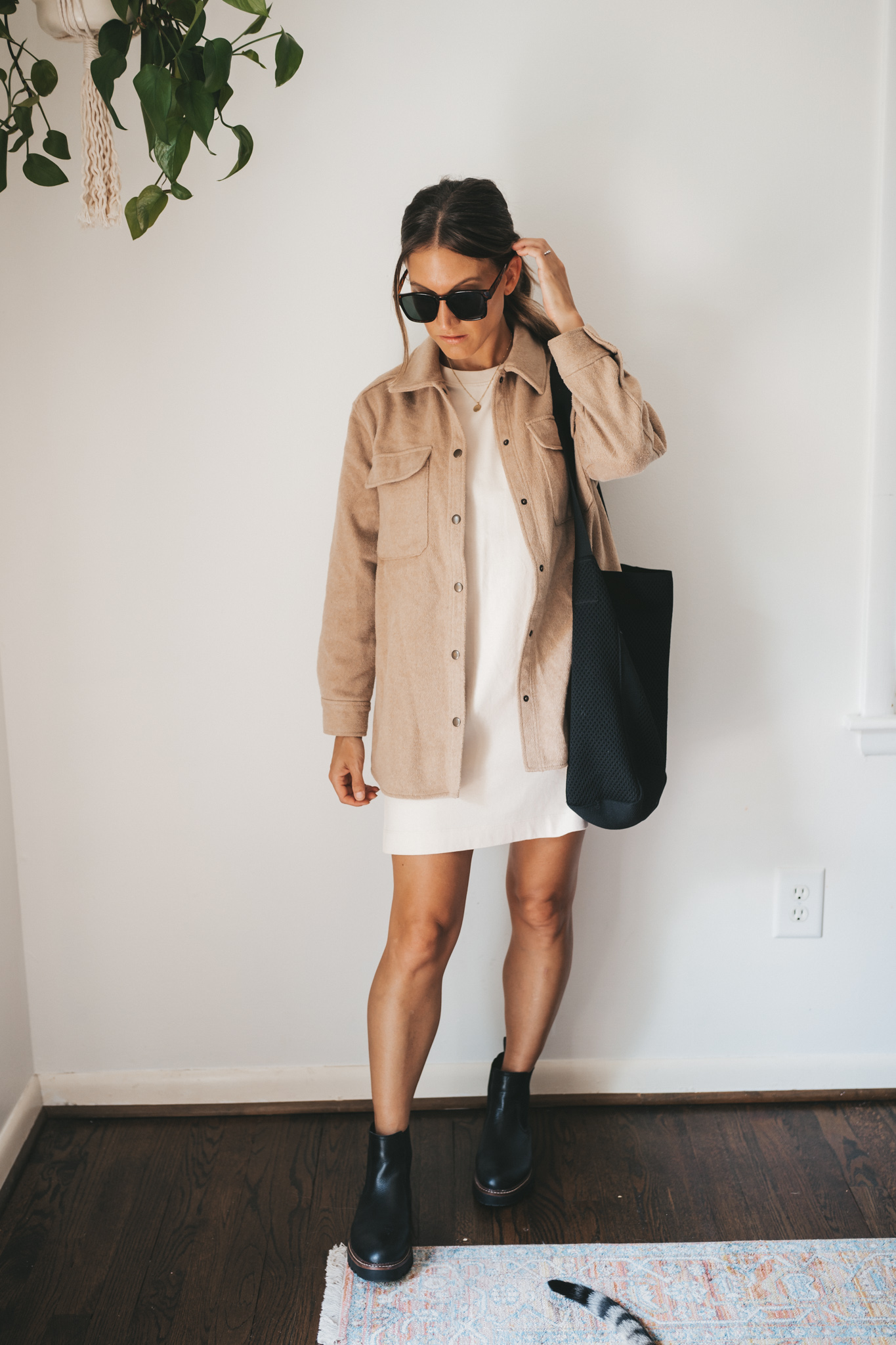 ashley wearing a cream colored t-shirt dress, tan shacket, black chunky Chelsea boots, and tortoise shell sunglasses