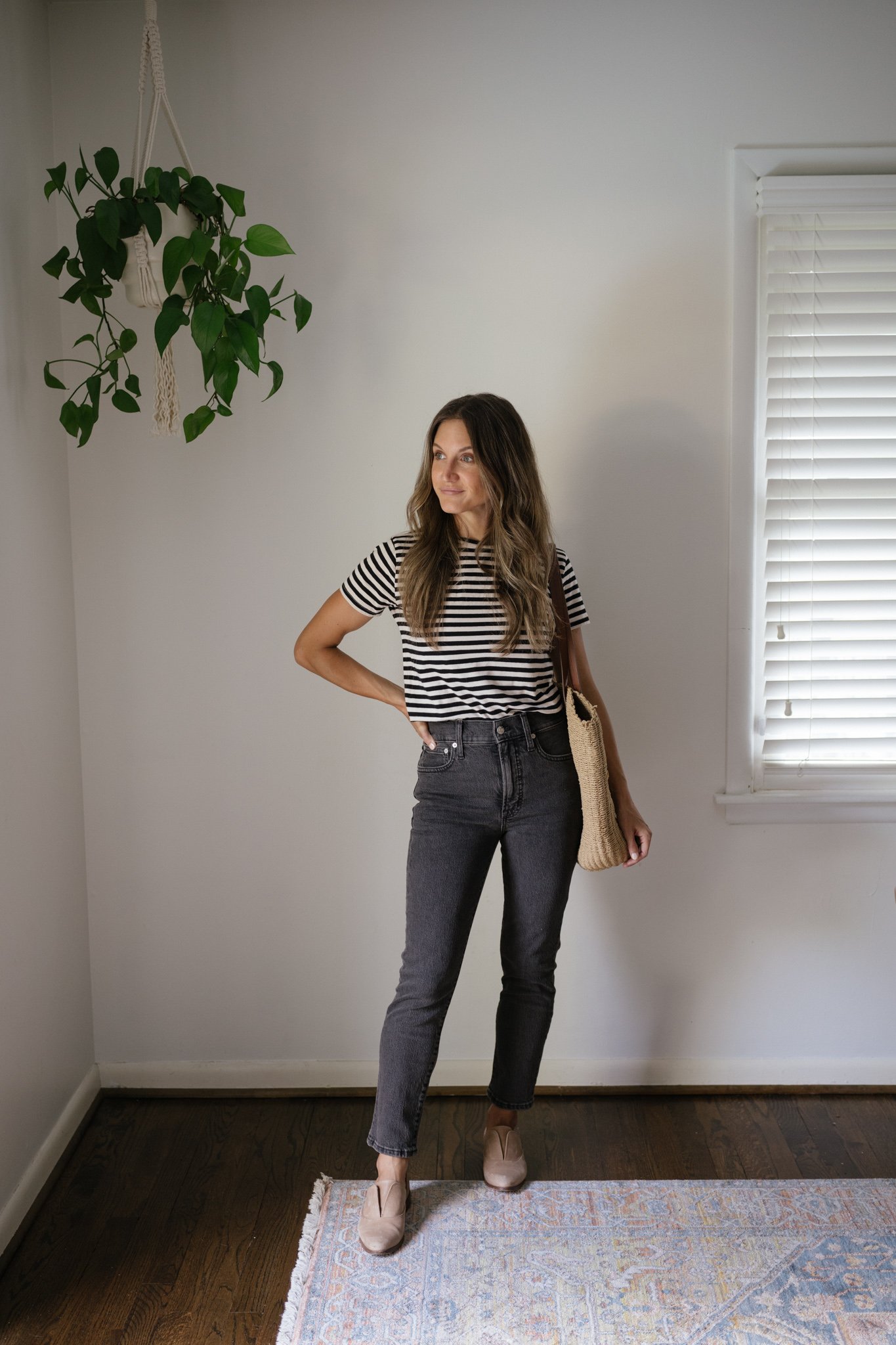 ashley wearing a black and white striped tee, washed black denim, and tan oxfords with a woven tote bag