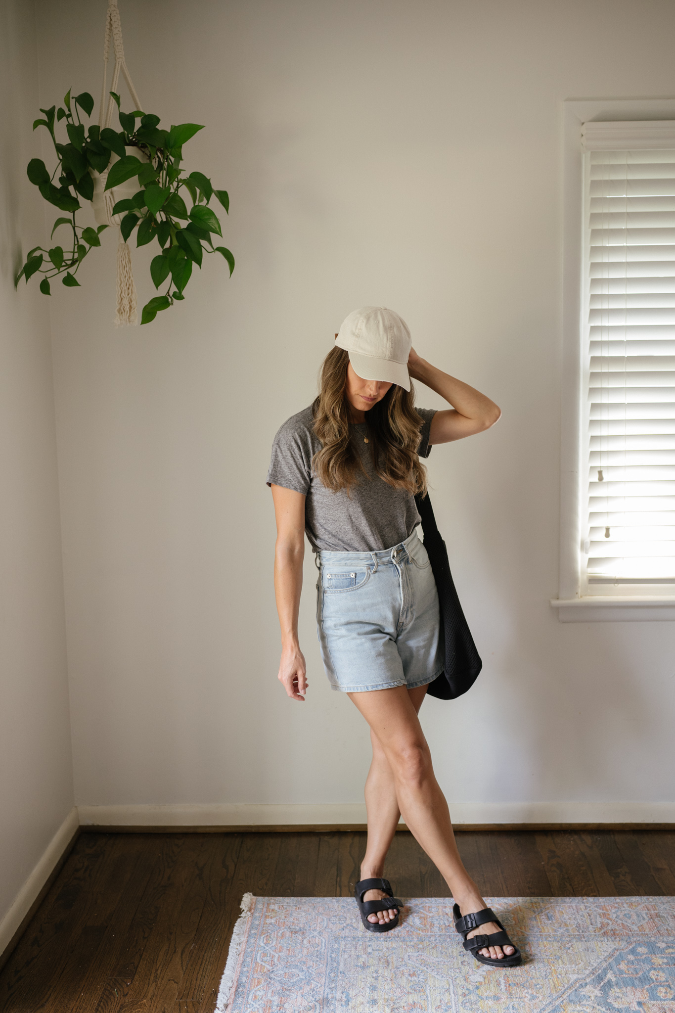 outfit idea for Seattle in the summer with a gray tee, light wash denim shorts, black Birkenstocks, and a cream colored baseball hat
