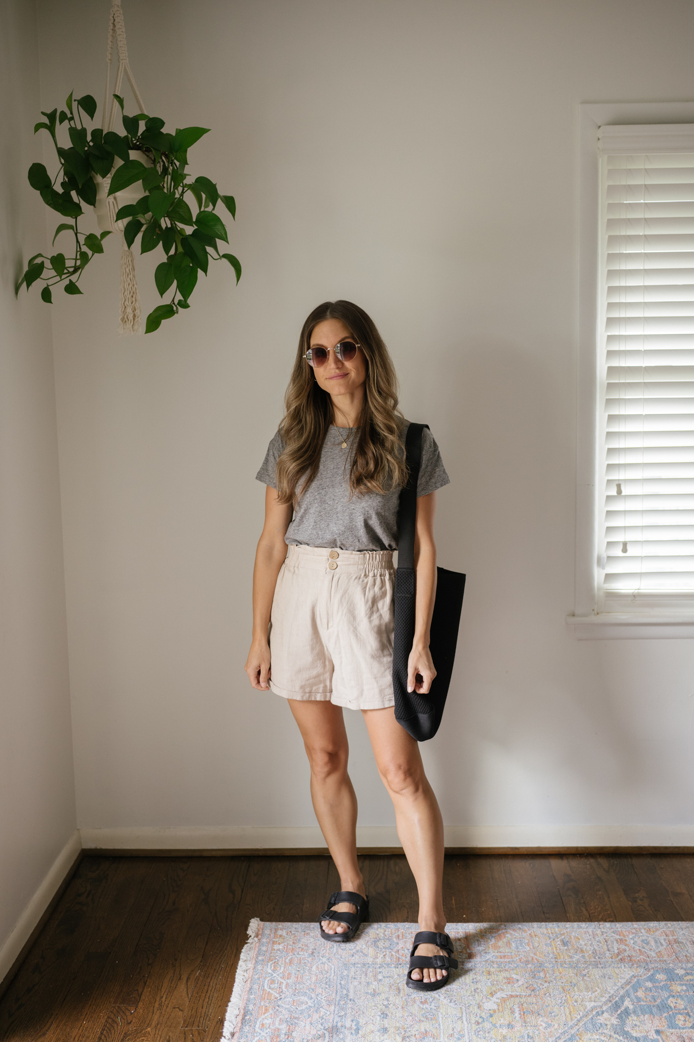 outfit idea for Seattle in the summer with a gray tee, tan linen shorts, black Birkenstocks, a black tote bag, and round sunglasses