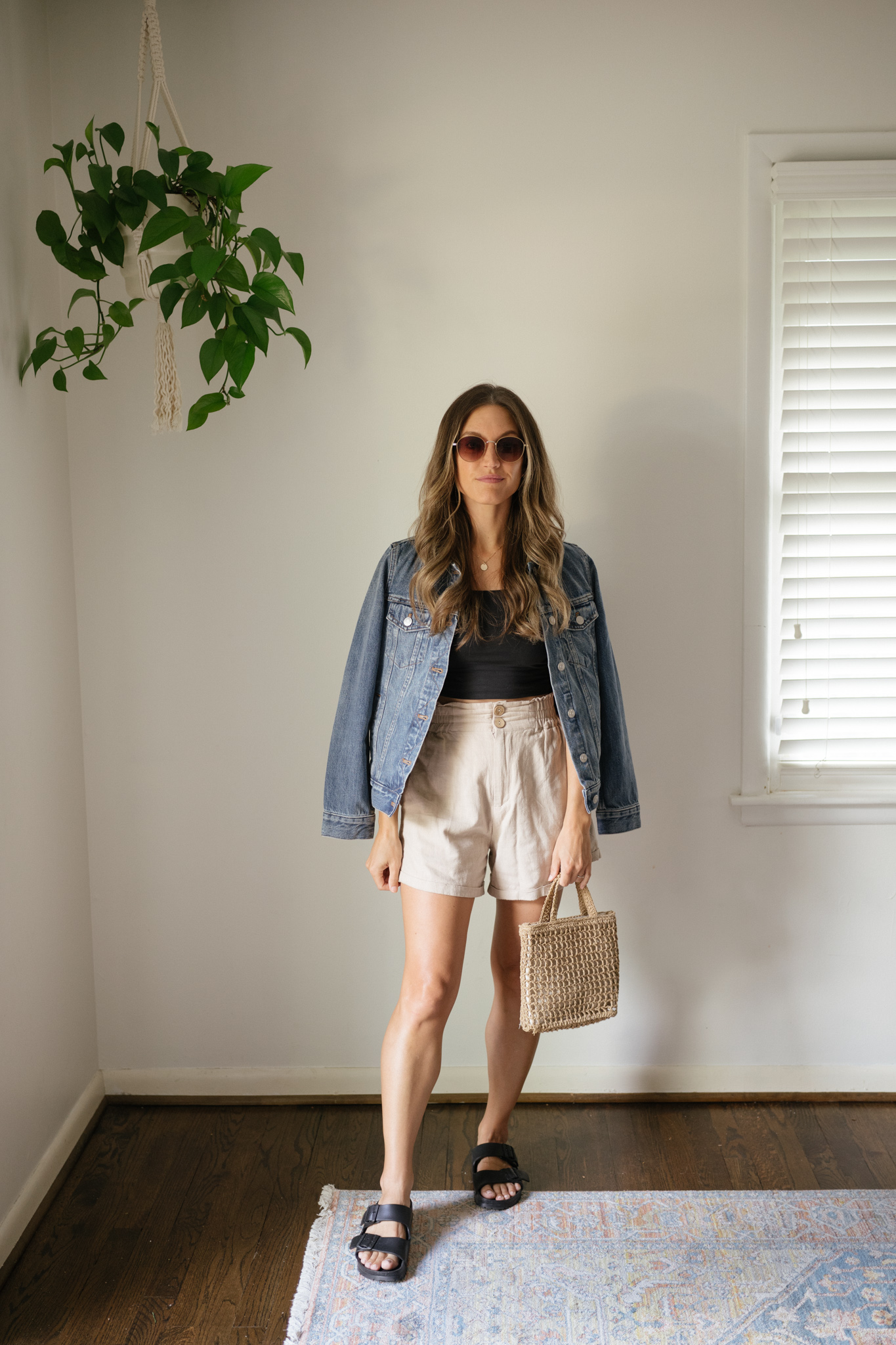 outfit idea for Seattle in the summer with a black cropped tank, linen shorts, a denim jacket worn over the shoulders and black Birkenstocks
