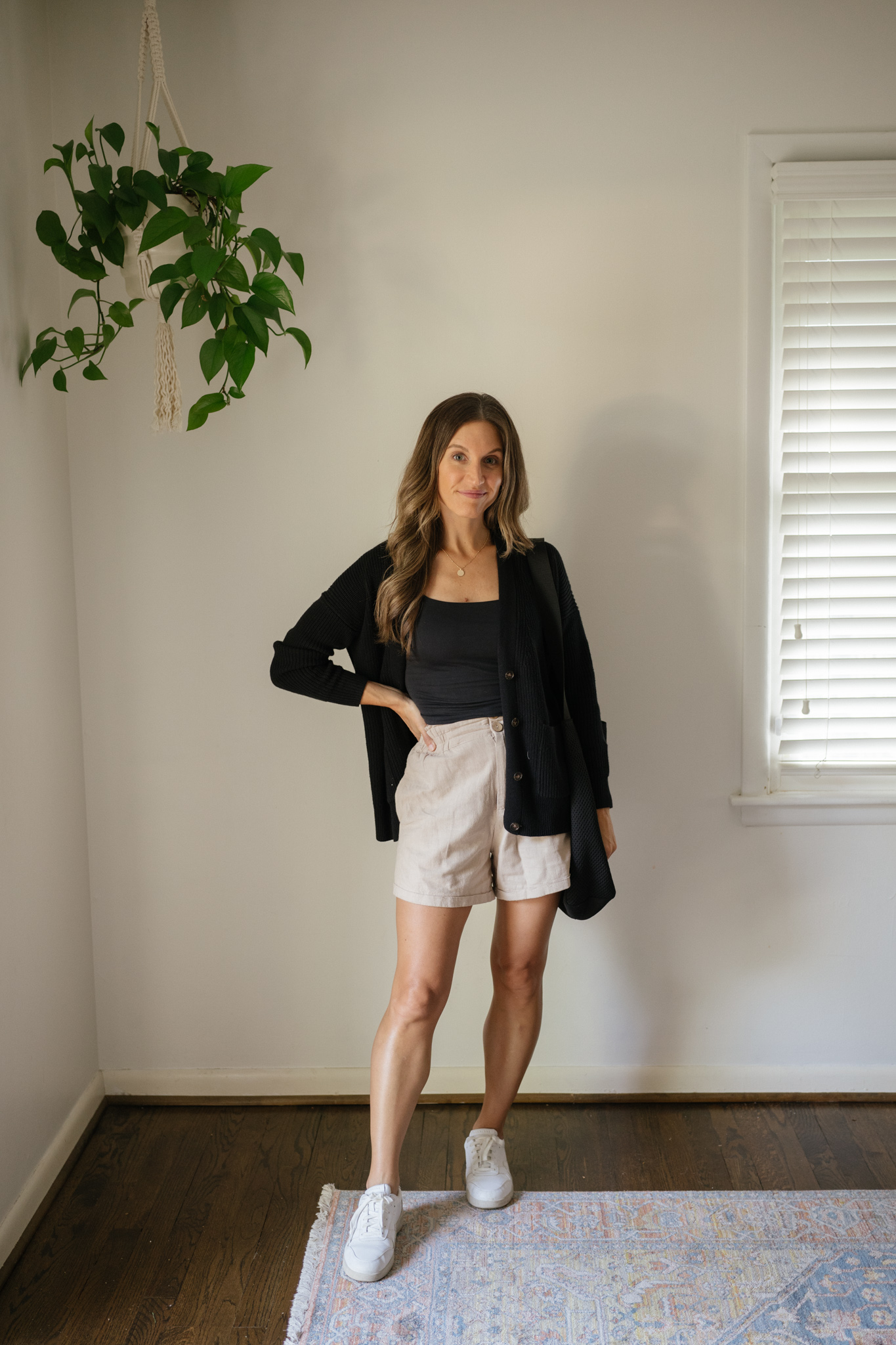 outfit idea for Seattle in the summer with a black cropped tank, black cardigan, tan linen shorts, and white sneakers