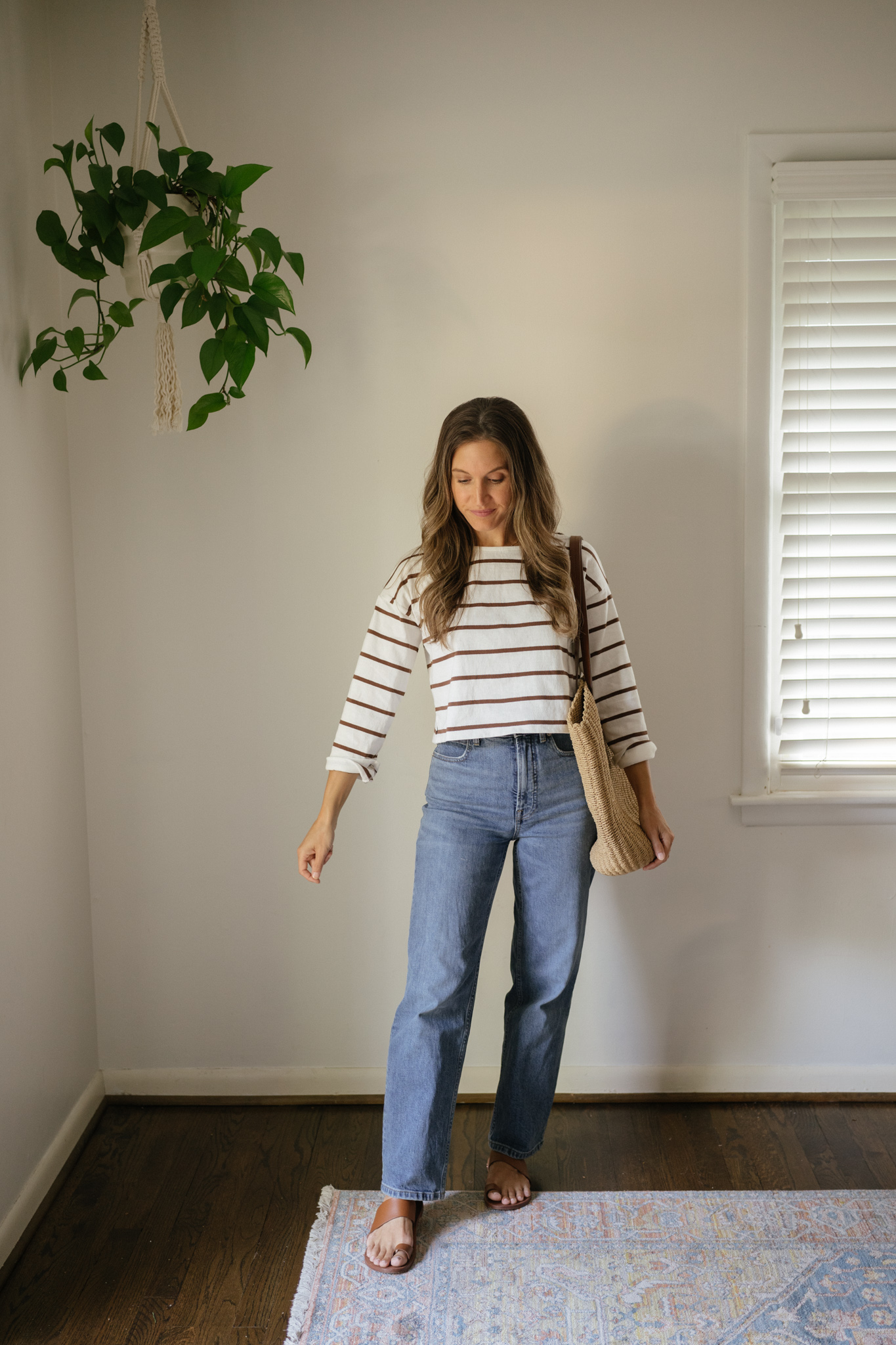 outfit idea for Seattle in the summer with a striped top, mid-wash straight denim, brown leather toe ring sandals, and a woven tote bag