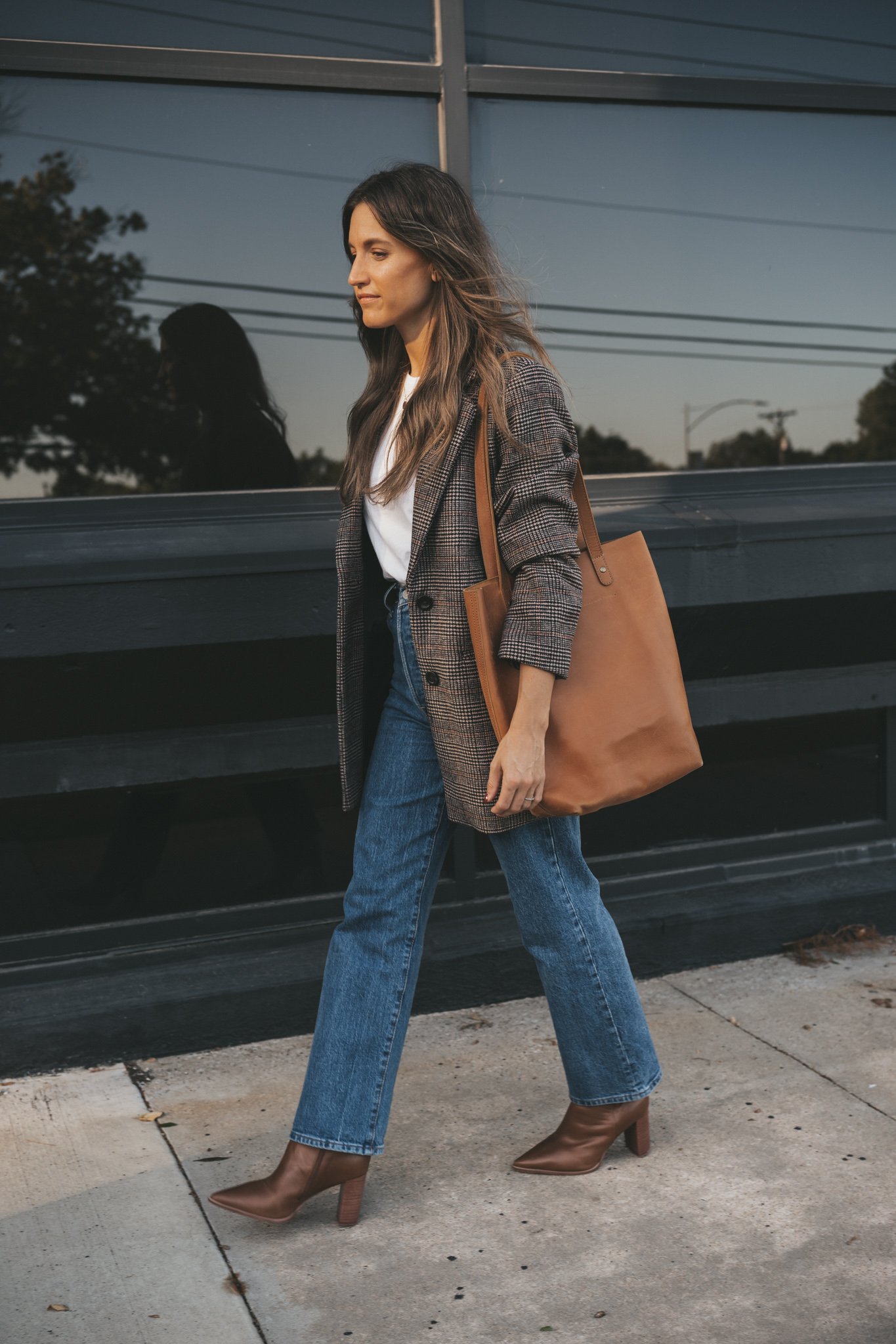 a plaid blazer outfit with a white tee, straight denim, brown ankle boots, and a cognac leather tote bag