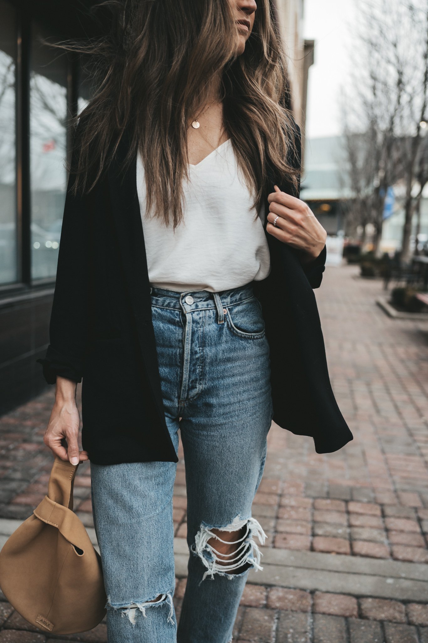 ashley wearing a black blazer, white cami, and distressed denim