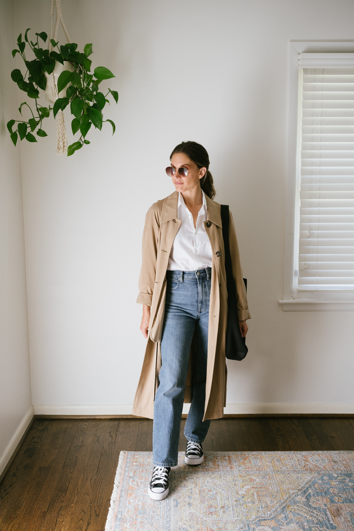 a white button down outfit with denim, high top Converse, and a trench coat