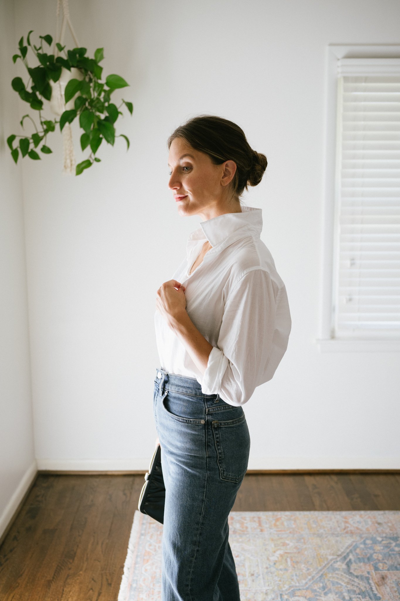ashley wearing a white button down, denim, and a clutch bag