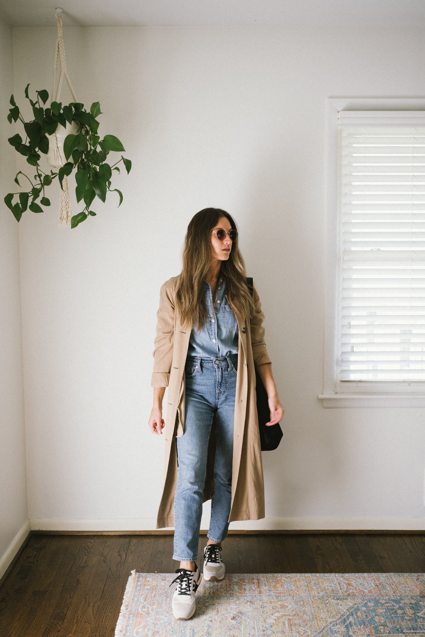 a denim on denim look with a trench coat and casual sneakers