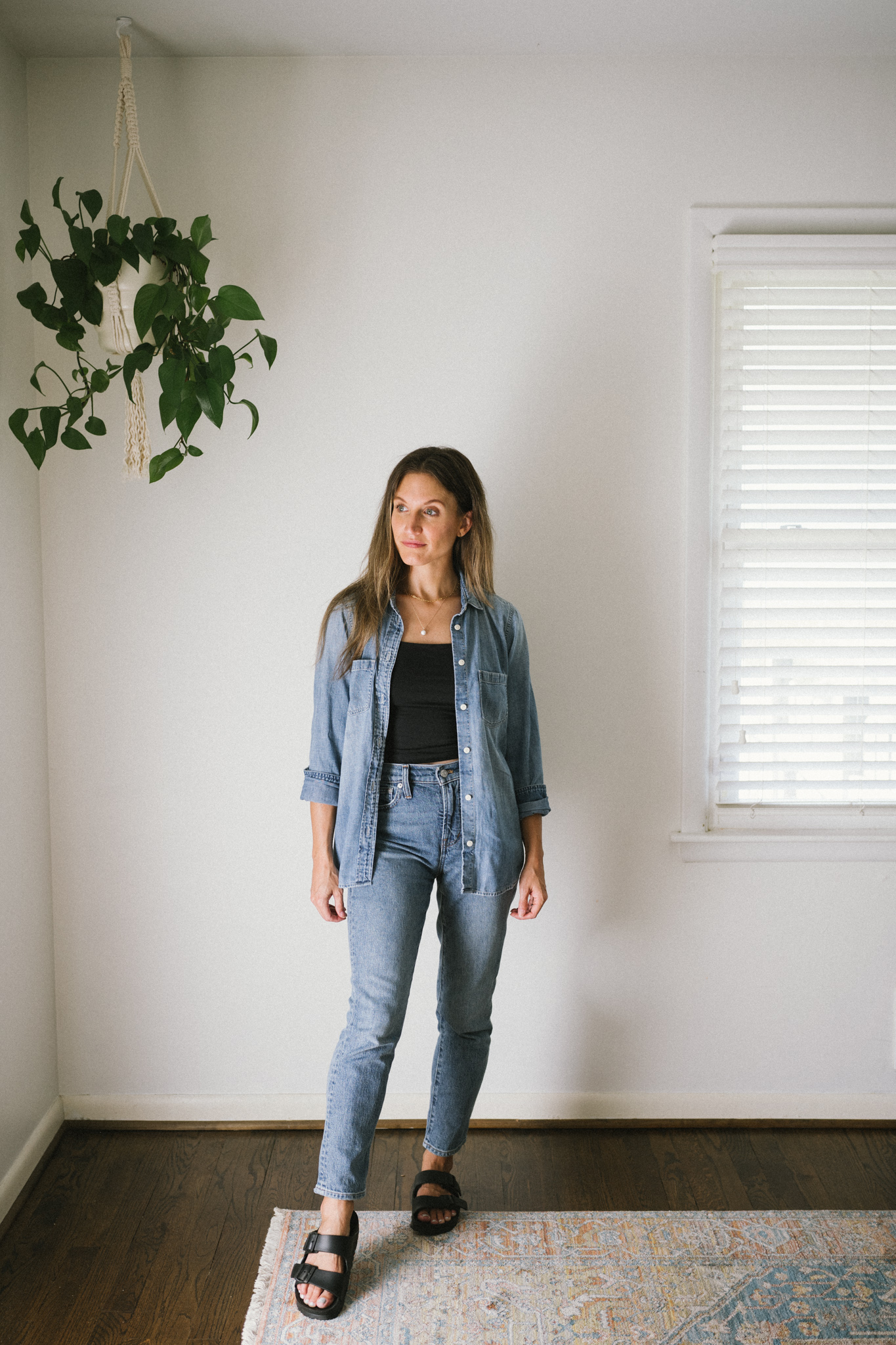 a denim on denim outfit with a black crop top and black birkenstock sandals
