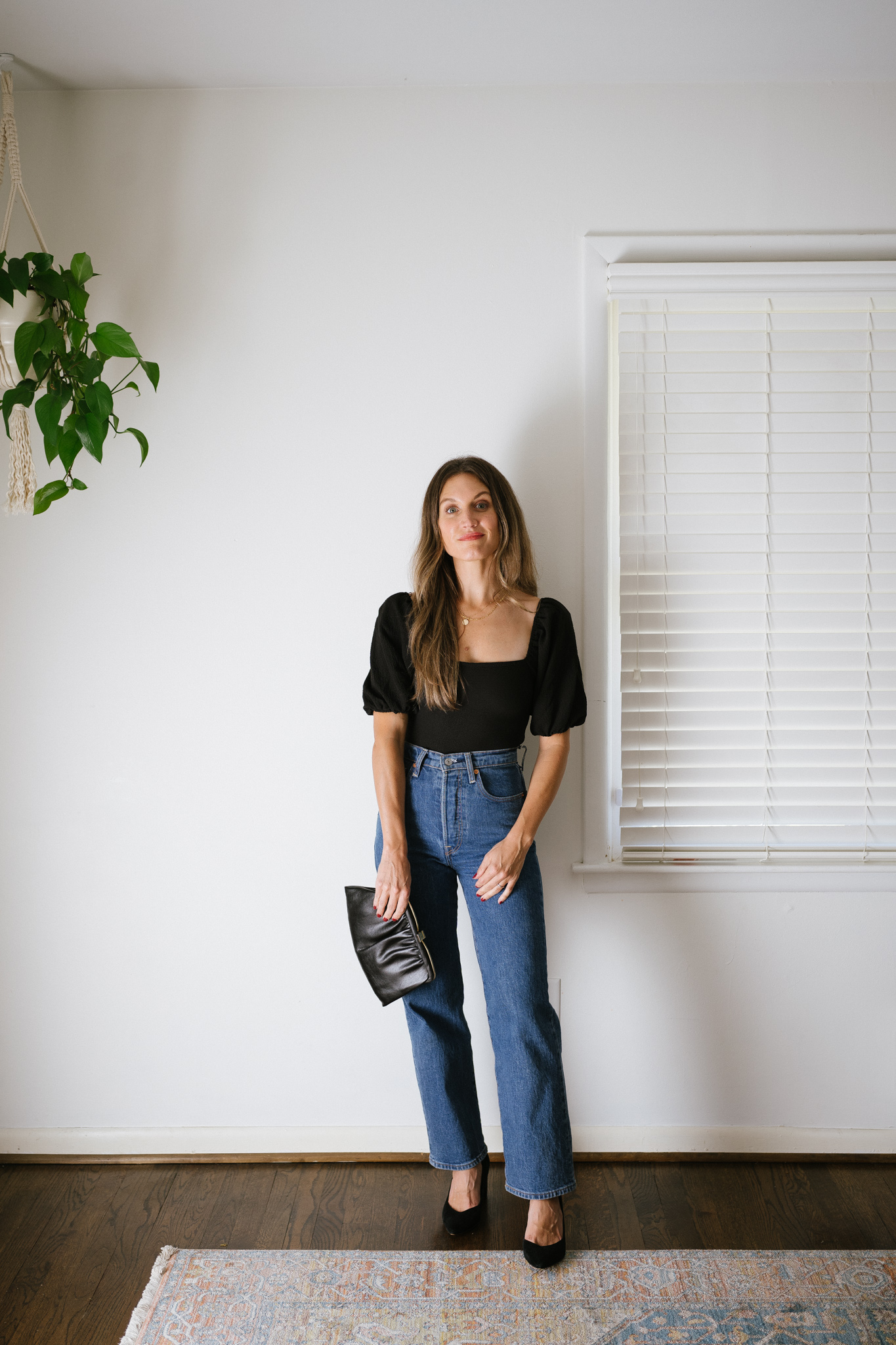 fall date night outfit with a black puff sleeve bodysuit and high waisted denim and black pumps