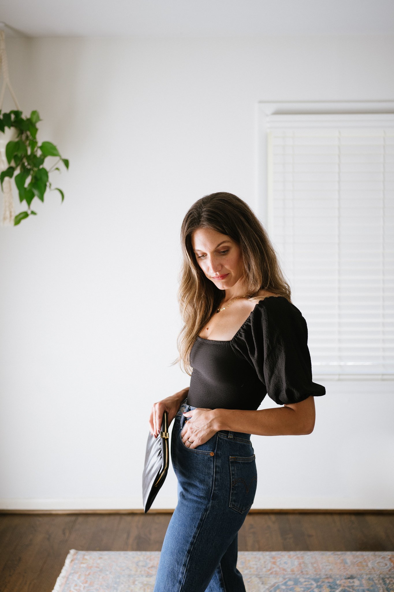 fall date night outfit with a black puff sleeve bodysuit and high waisted denim